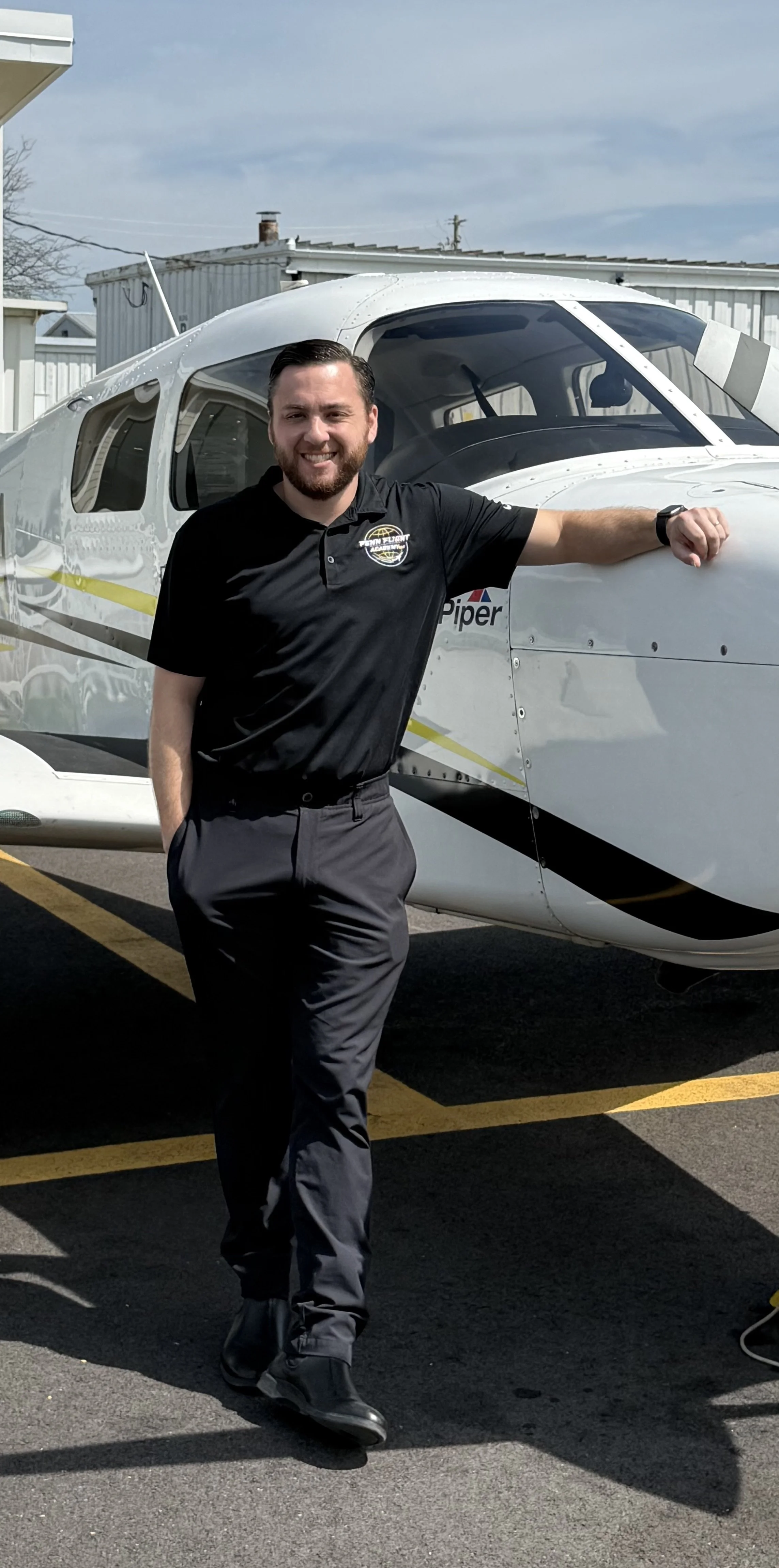 Person in sunglasses wearing a Penn Flight School polo shirt, standing next to an aircraft propeller.