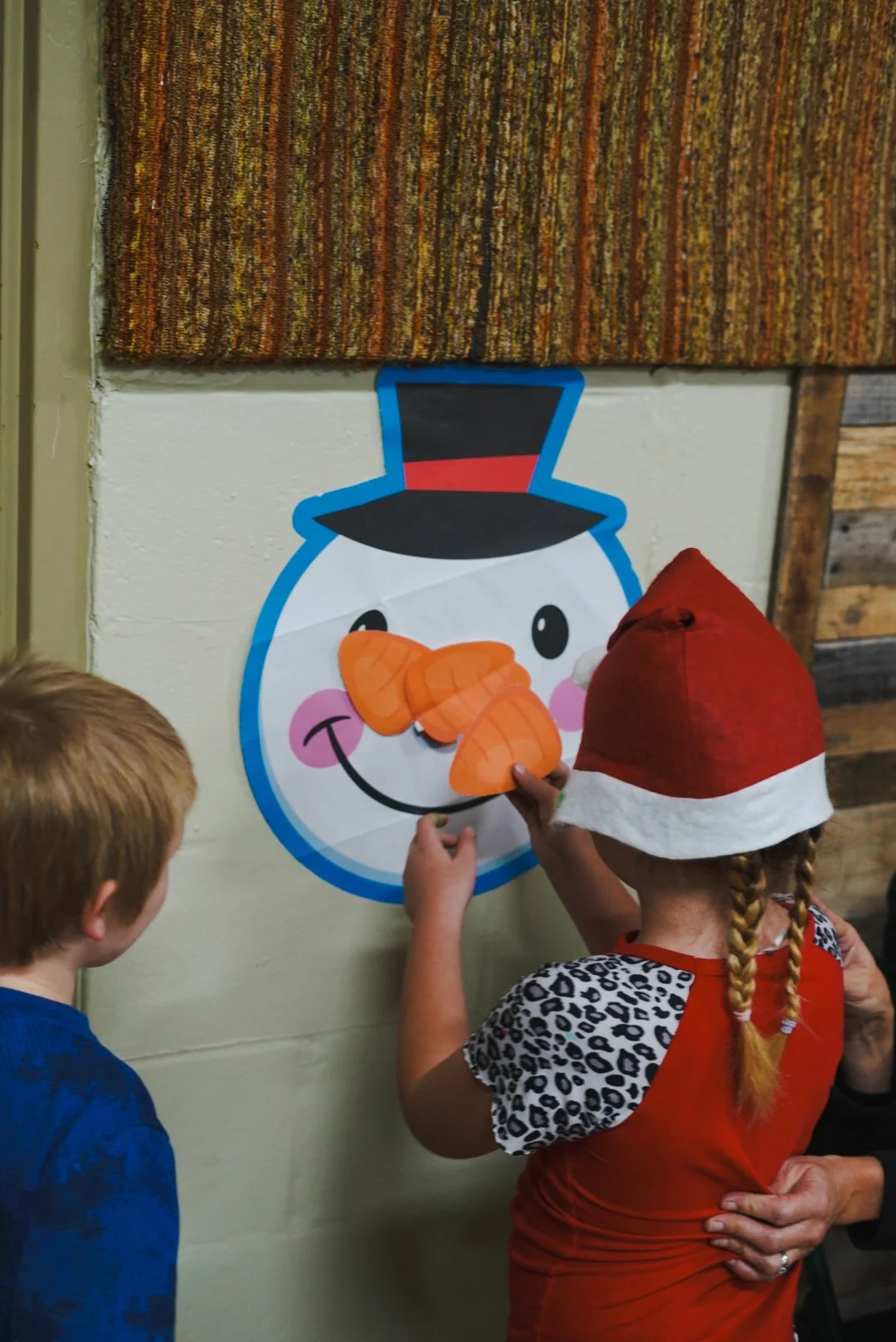 Children decorating a snowman's face with paper carrots