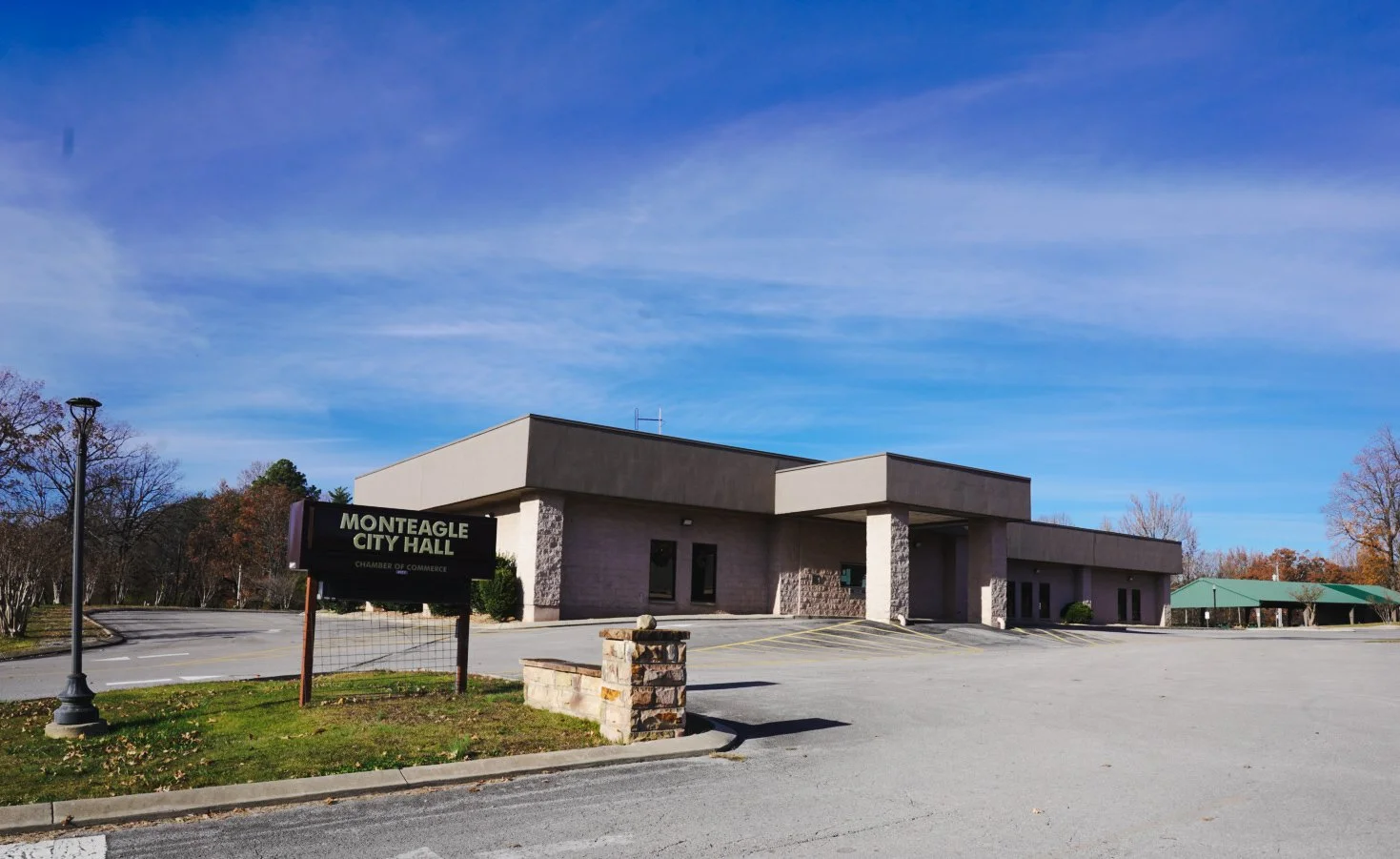 Exterior of Monteagle City Hall building with parking lot, sign, and clear blue sky.