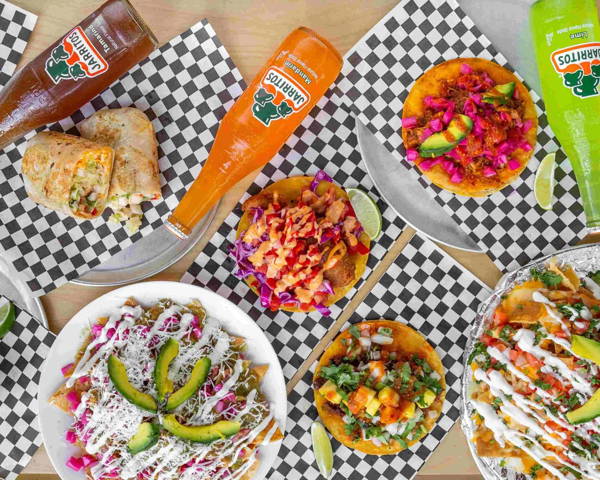 Fresh tacos, guacamole, and Jarritos sodas served on a patio table at Piñata Tacos on Dundas Street West in Toronto