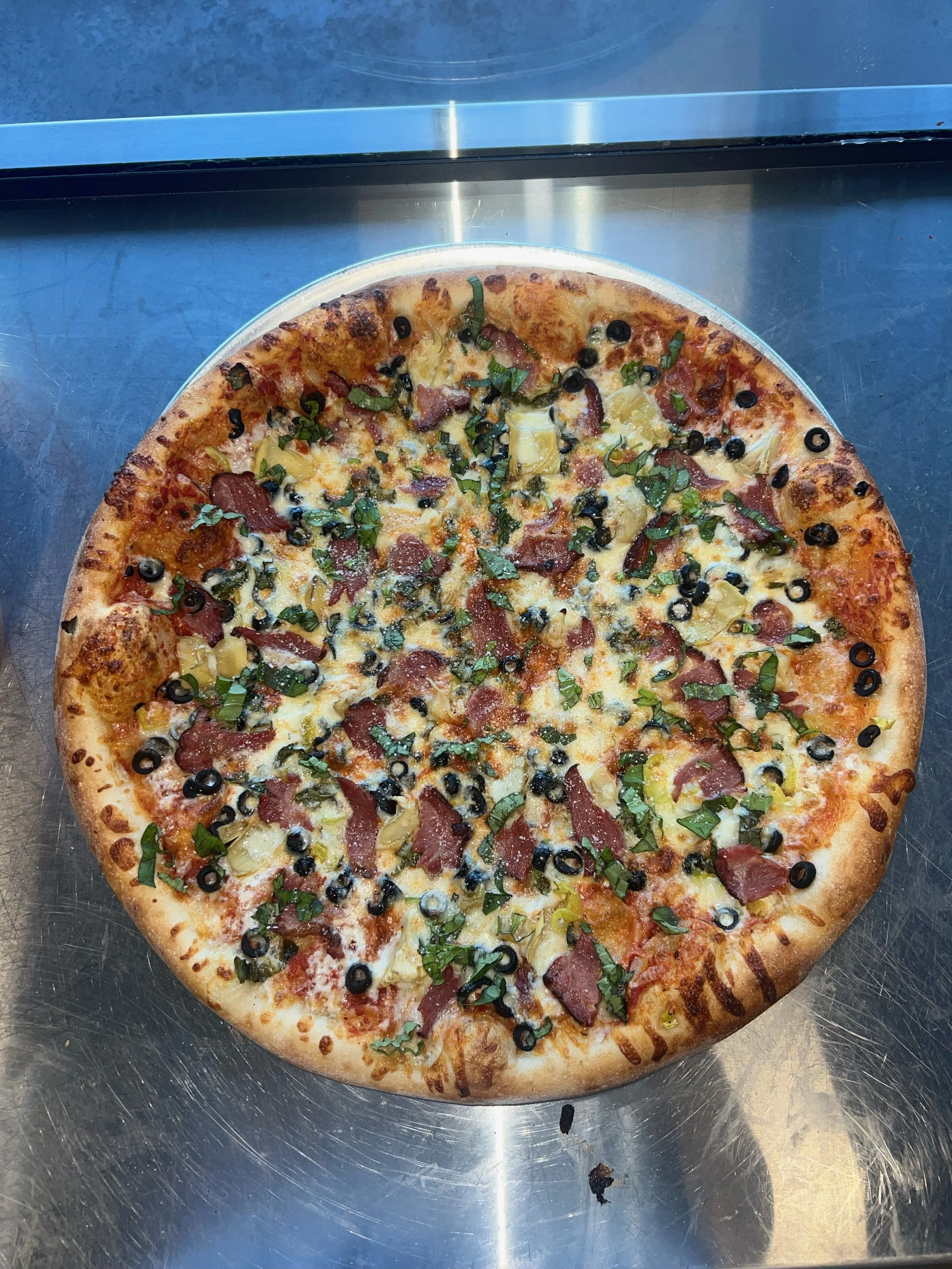 A whole pizza, custom made, on our long-fermented sourdough crust, topped with olives, basil, and bacon