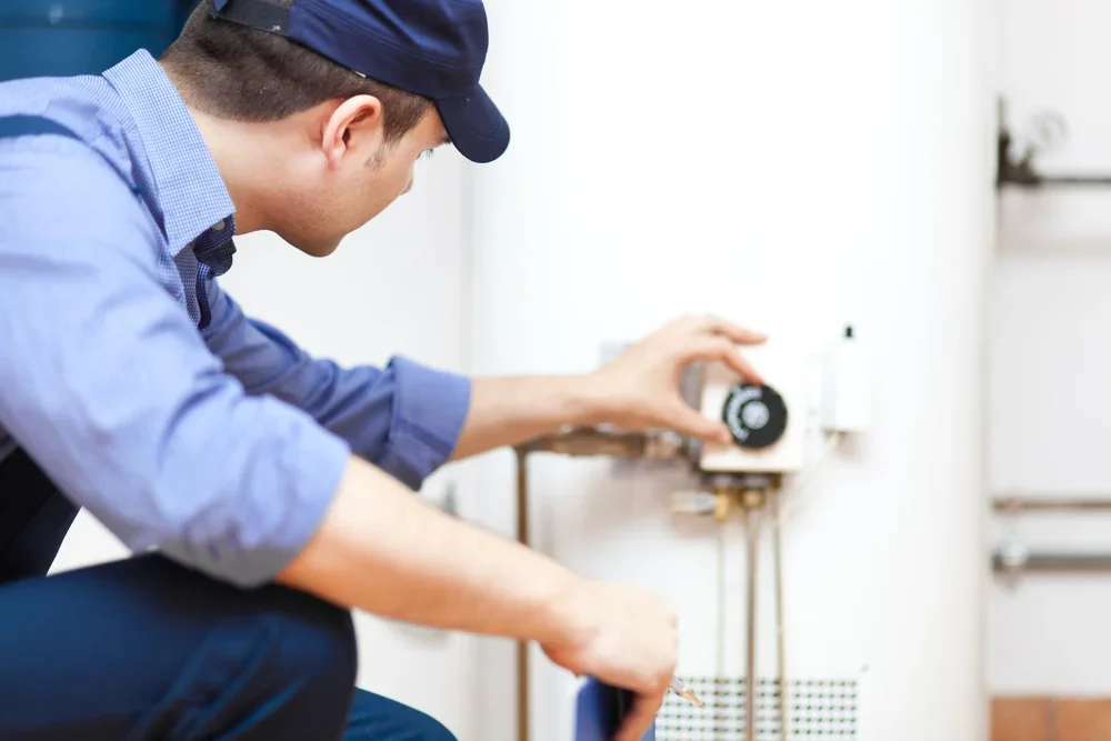 A technician adjusting a heating control unit on a water heater.