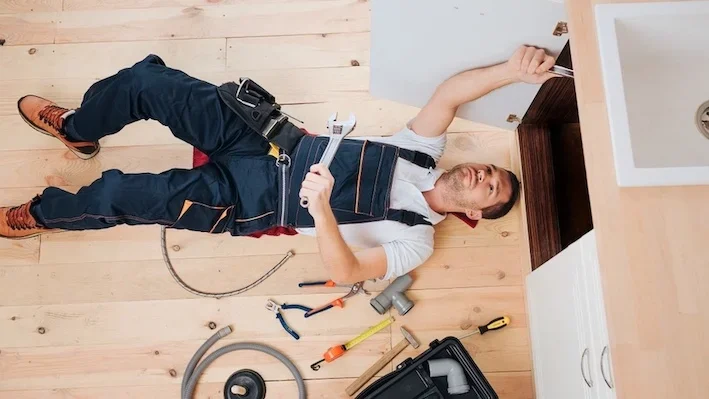 Plumber fixing leaking kitchen sink