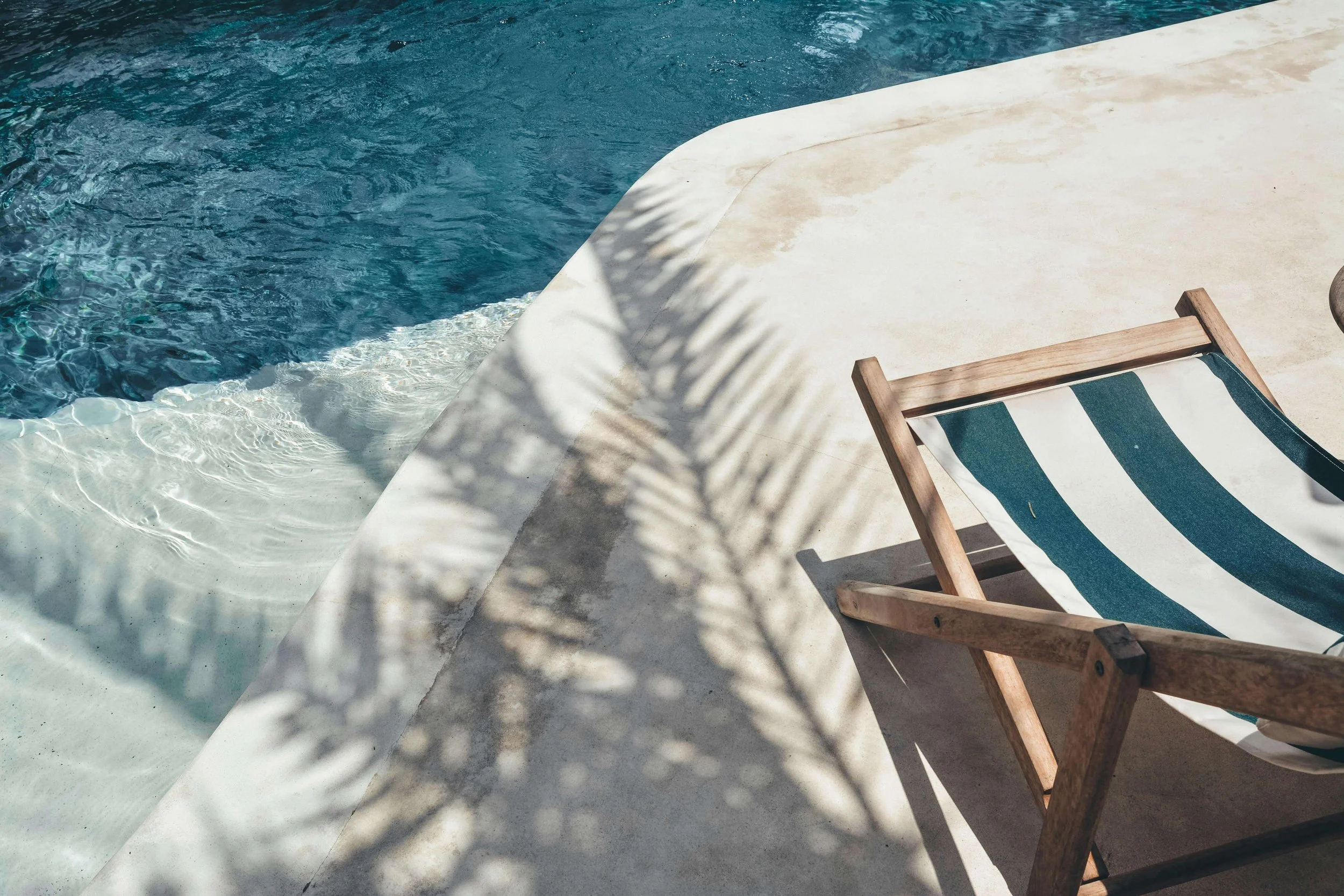 A striped lounge chair beside a pool. Are you exhausted by the pressure to create the perfect summer and never feeling like enough? Emotional regulation therapy in Davie, FL, can help you release that pressure and find peace.