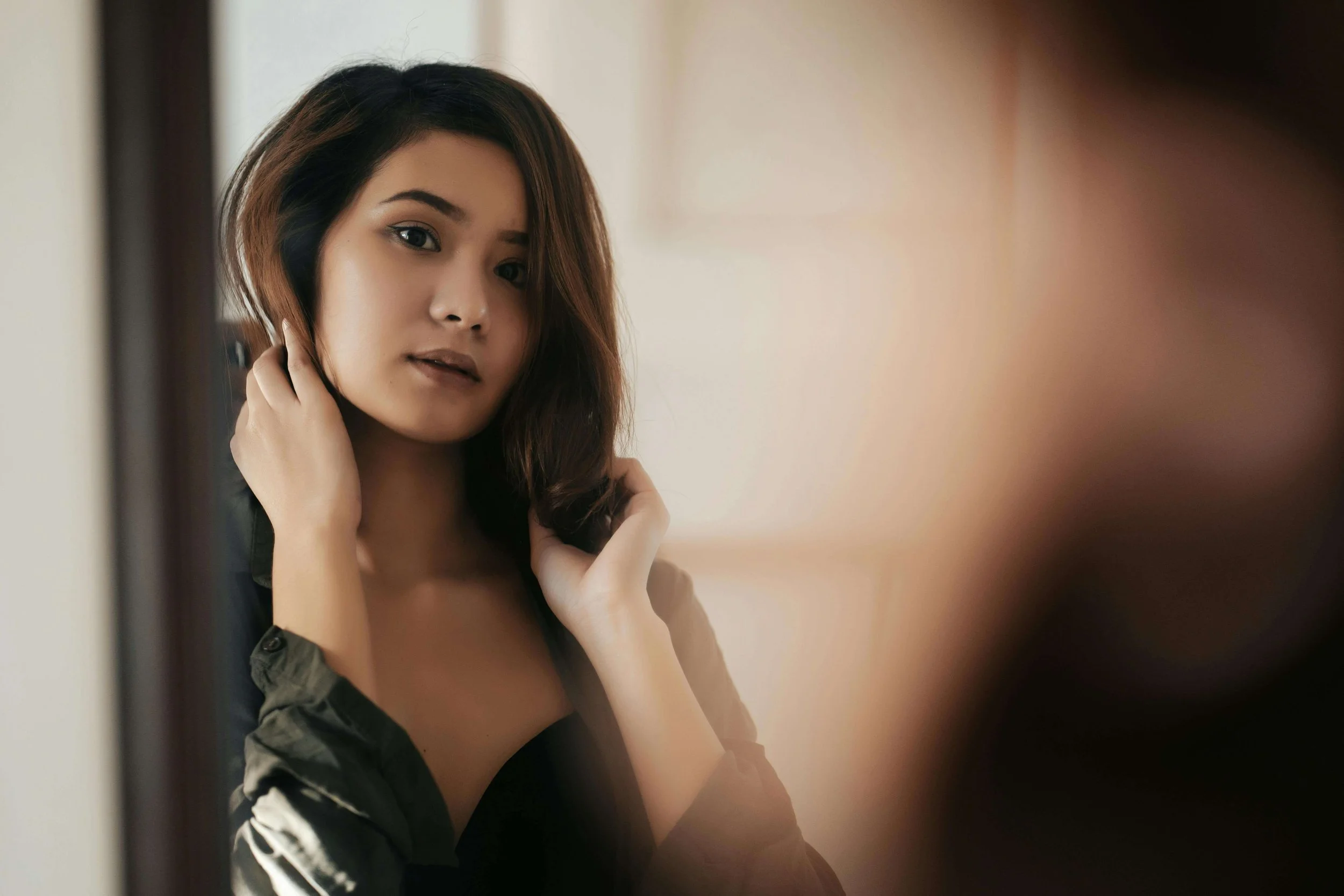 A woman gazes thoughtfully at her reflection. When self-esteem wavers, does it affect how you show up in relationships? Relationship therapy in Davie, FL, addresses the interplay between personal worth and partnership dynamics.