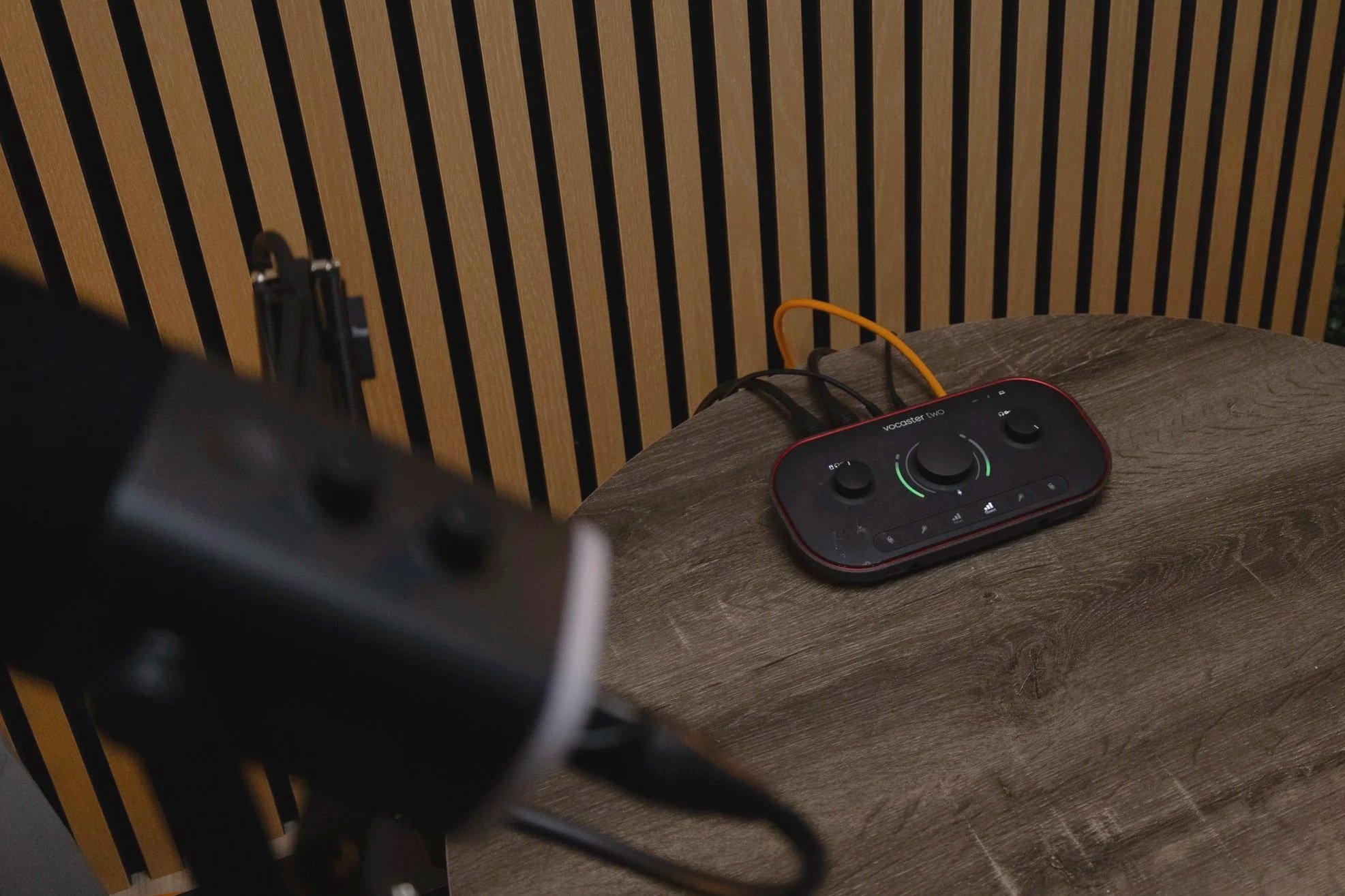 Black-and-white portrait of a young man in a suit holding a Canon DSLR camera, looking directly at the camera.