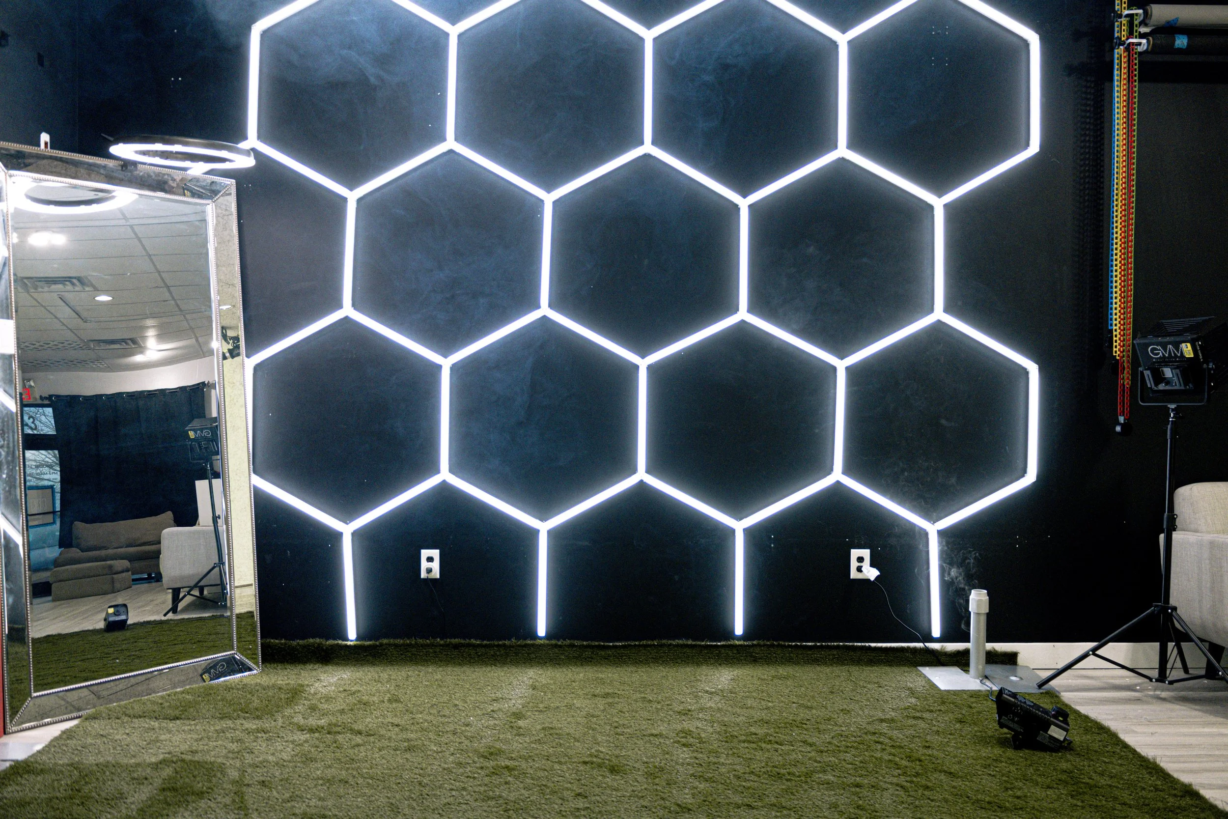 Black and white portrait of a young man with short, spiked hair, wearing a dark shirt, with a serious expression, crossed arms, a watch on his left wrist, and a bracelet on his right wrist, against a dark background.