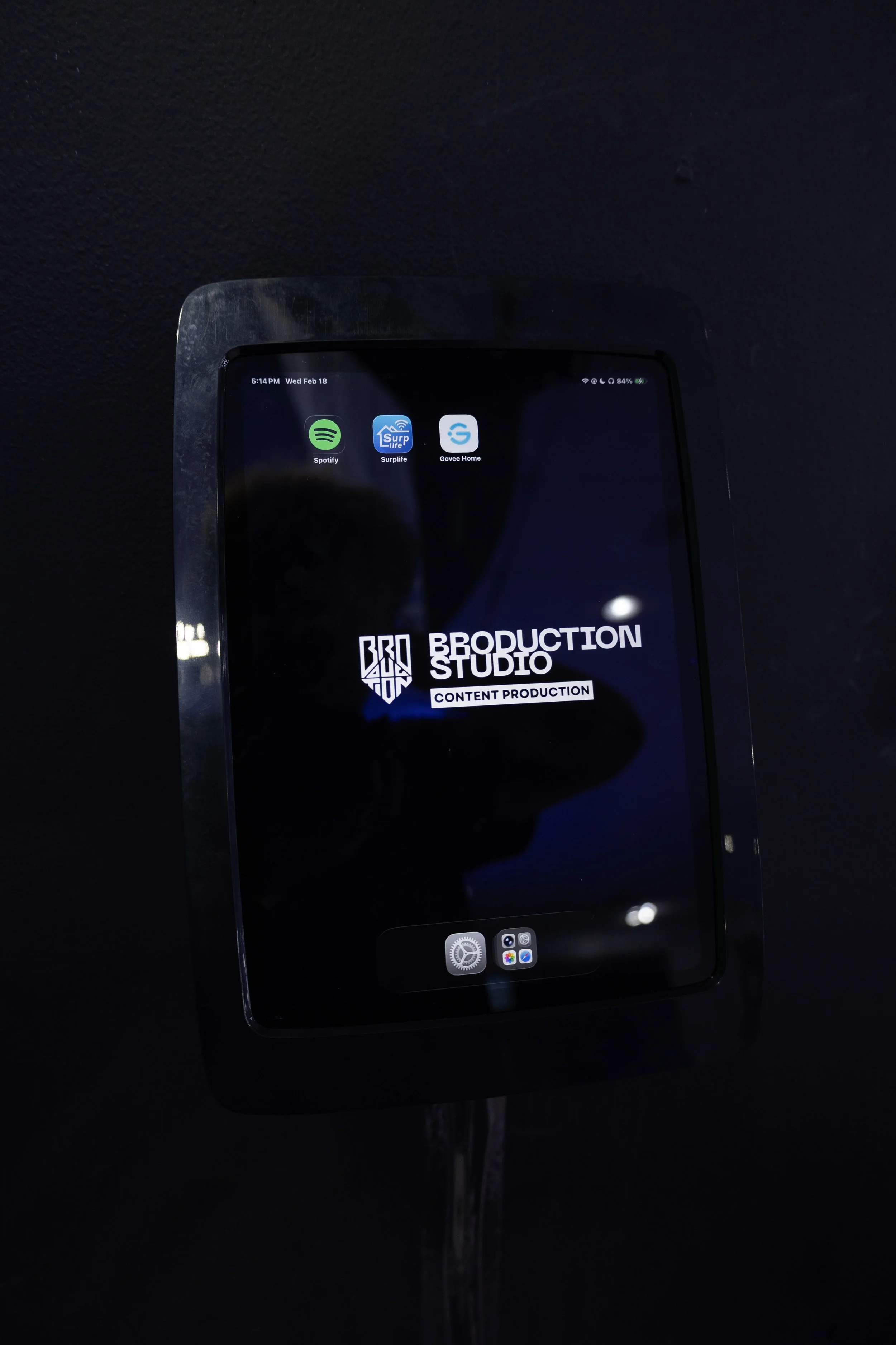 Black-and-white portrait of a young man in a suit holding a Canon DSLR camera, looking directly at the camera.
