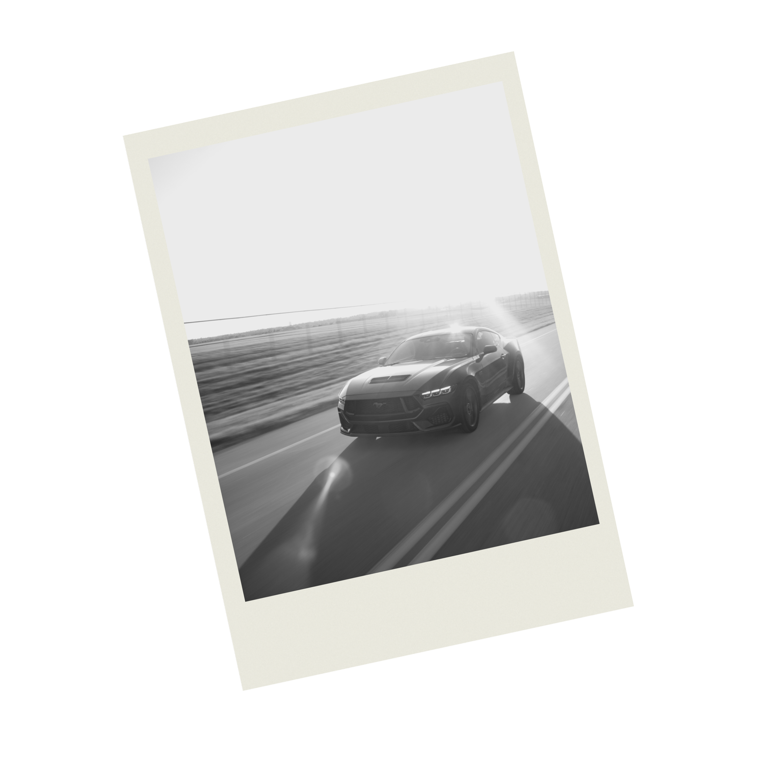 A black sports car driving on a highway with a flat landscape and a cloudy sky in the background, captured in black and white.