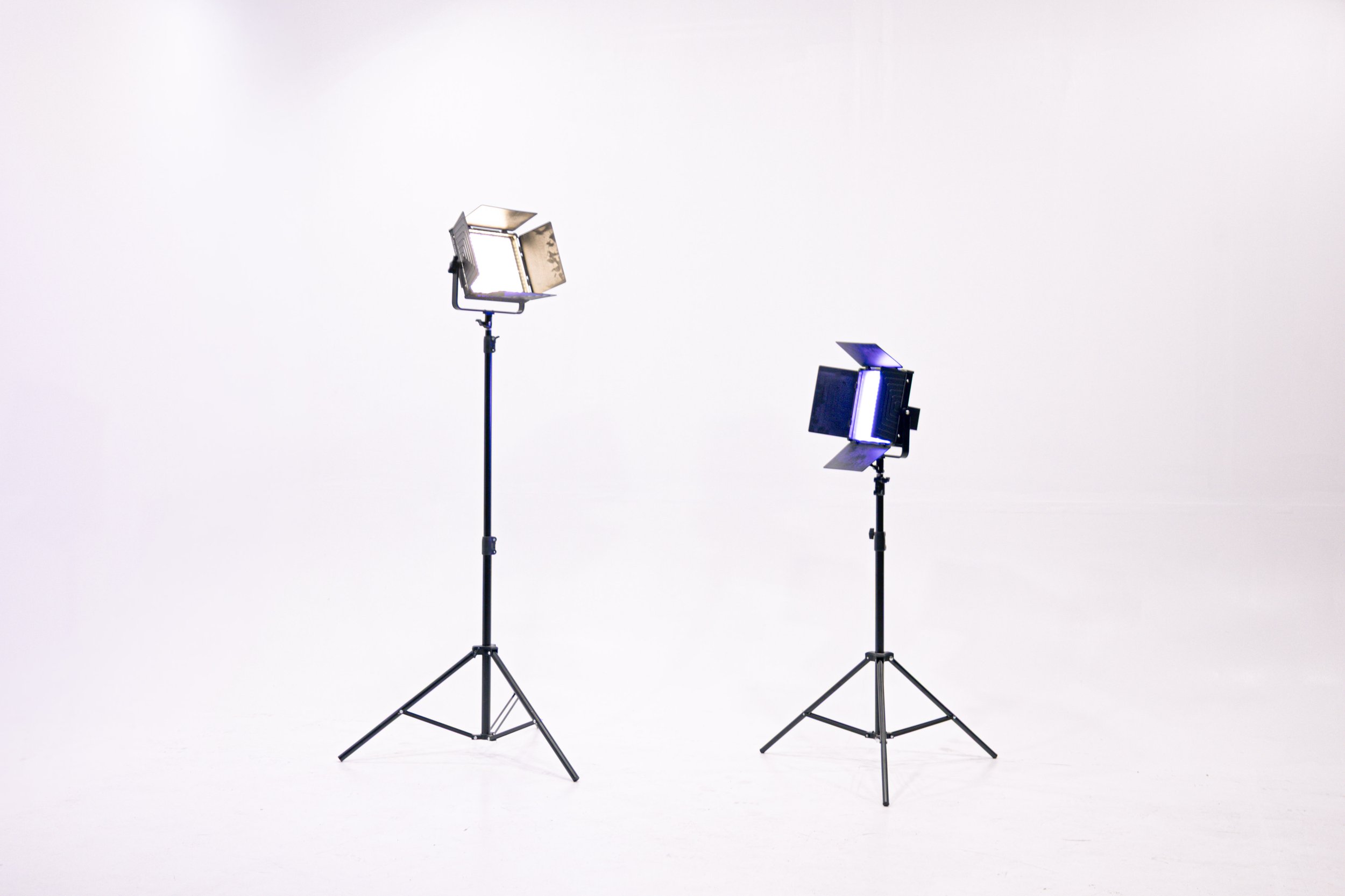 Black and white portrait of a young man with short, spiked hair, wearing a dark shirt, with a serious expression, crossed arms, a watch on his left wrist, and a bracelet on his right wrist, against a dark background.