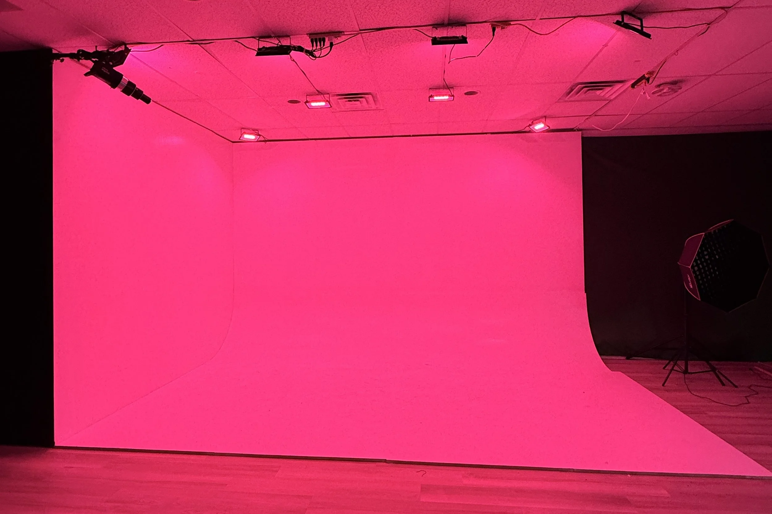 Black and white portrait of a young person holding a Canon camera, looking directly at the camera with a serious expression.