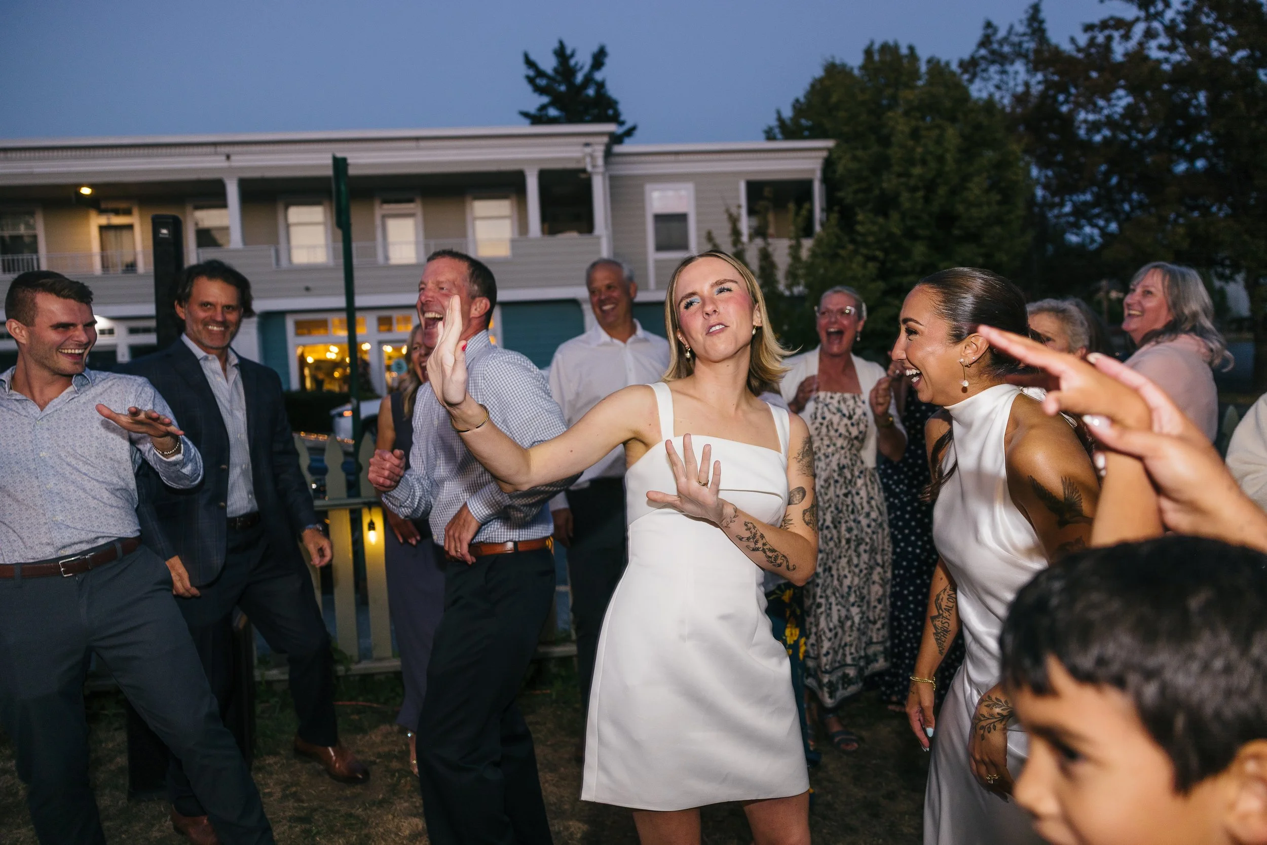 People dancing and celebrating outdoors during a gathering at dusk.