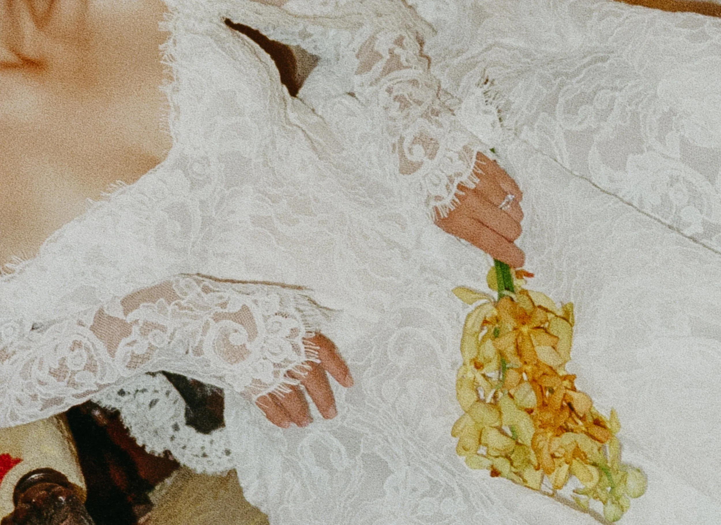 A person wearing a cream-colored lace dress holding a slice of pizza on a plate.