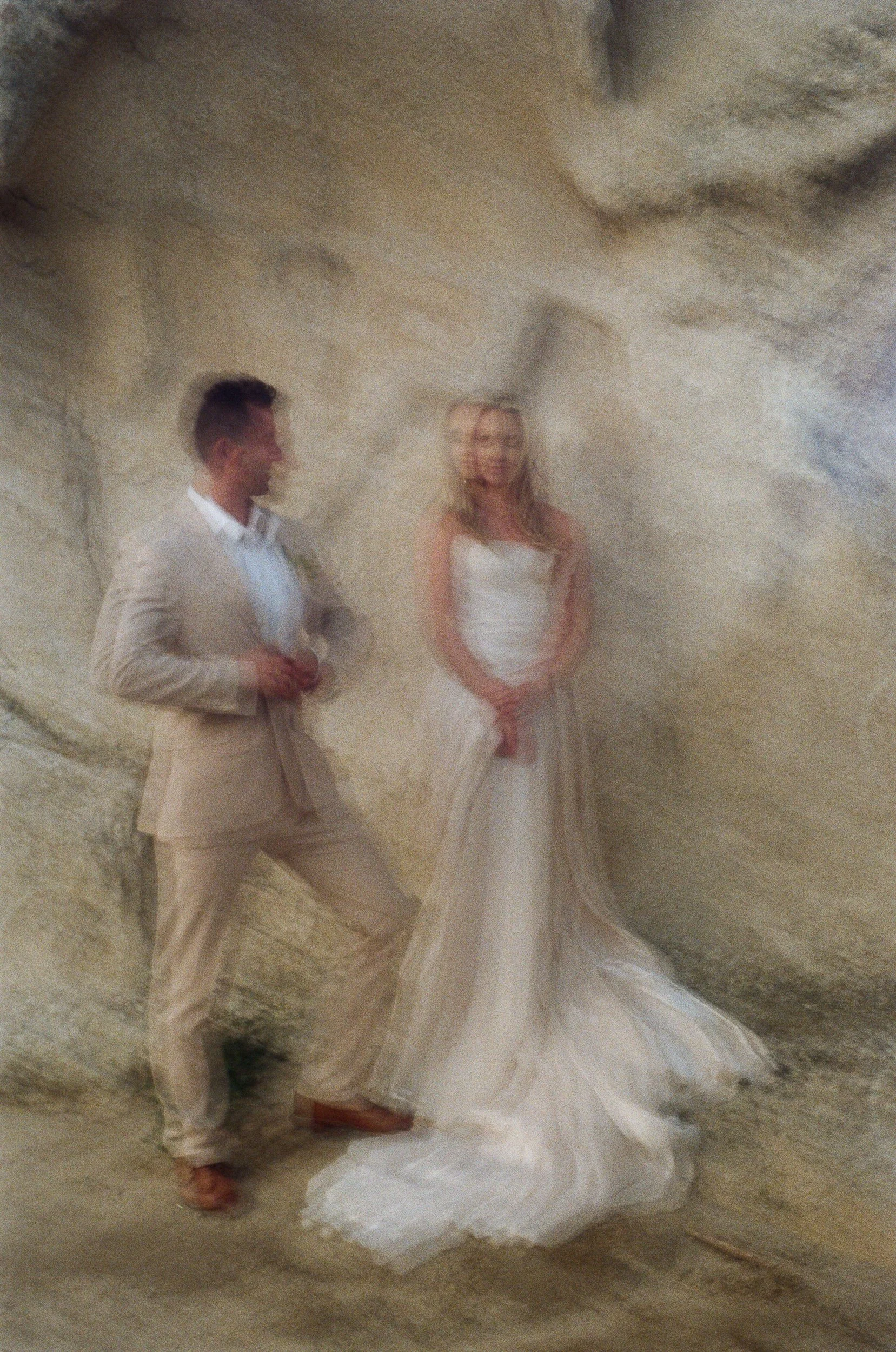 Blurry photo of a man and woman in wedding attire standing inside a cave.