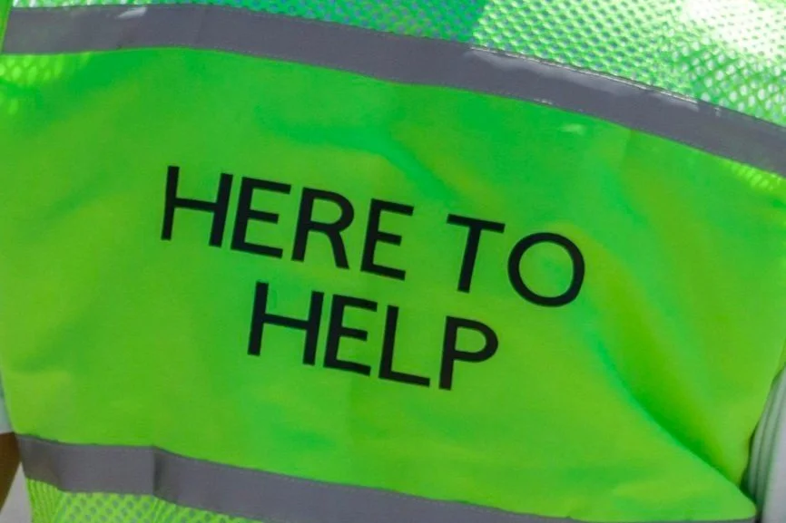 Bright yellow safety vest with the words "HERE TO HELP" printed in black.