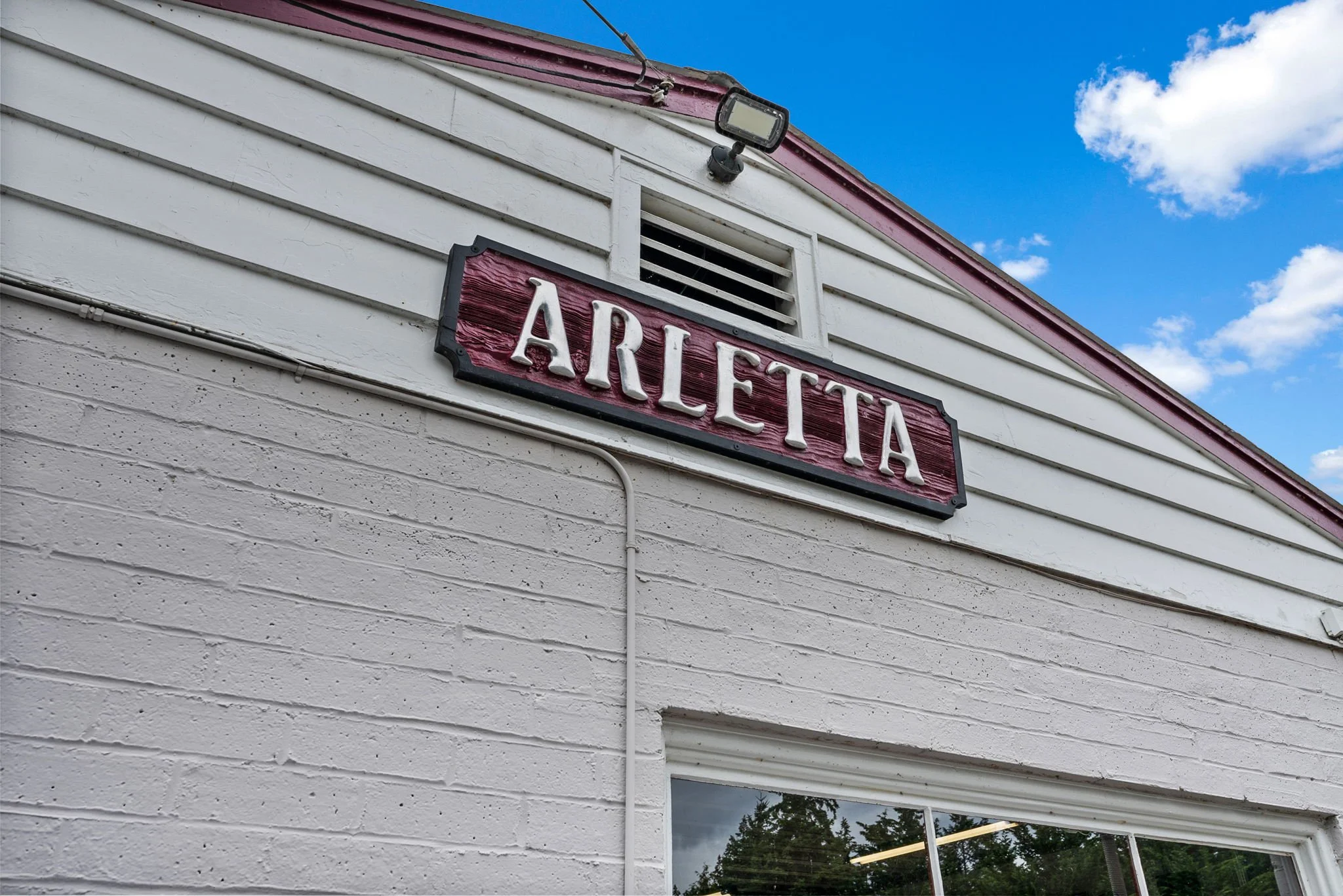Building with a sign that reads 'ARLETTAS' above a window, under a blue sky with clouds.