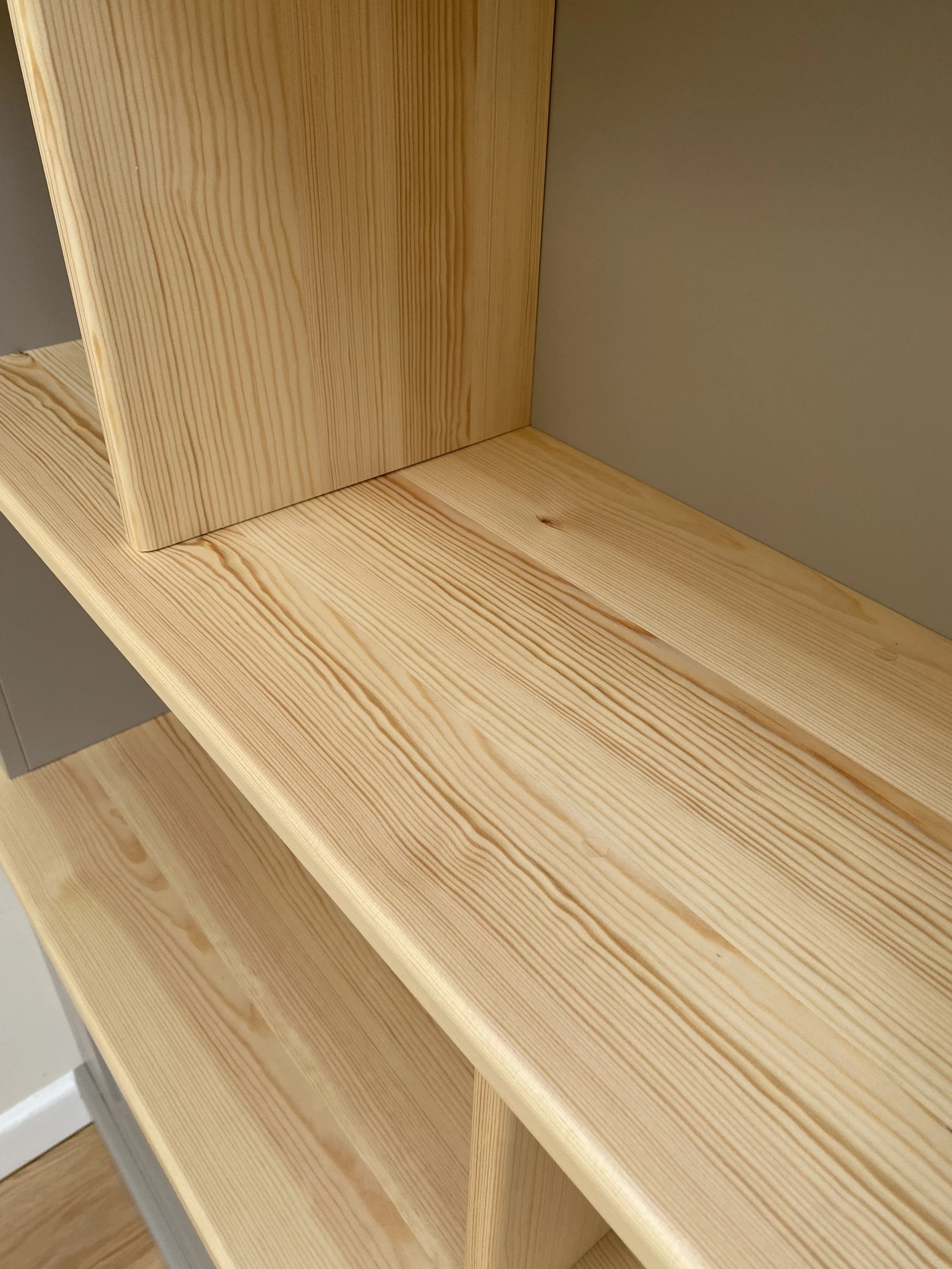 Close-up of unfinished wooden shelves and frame in a room.