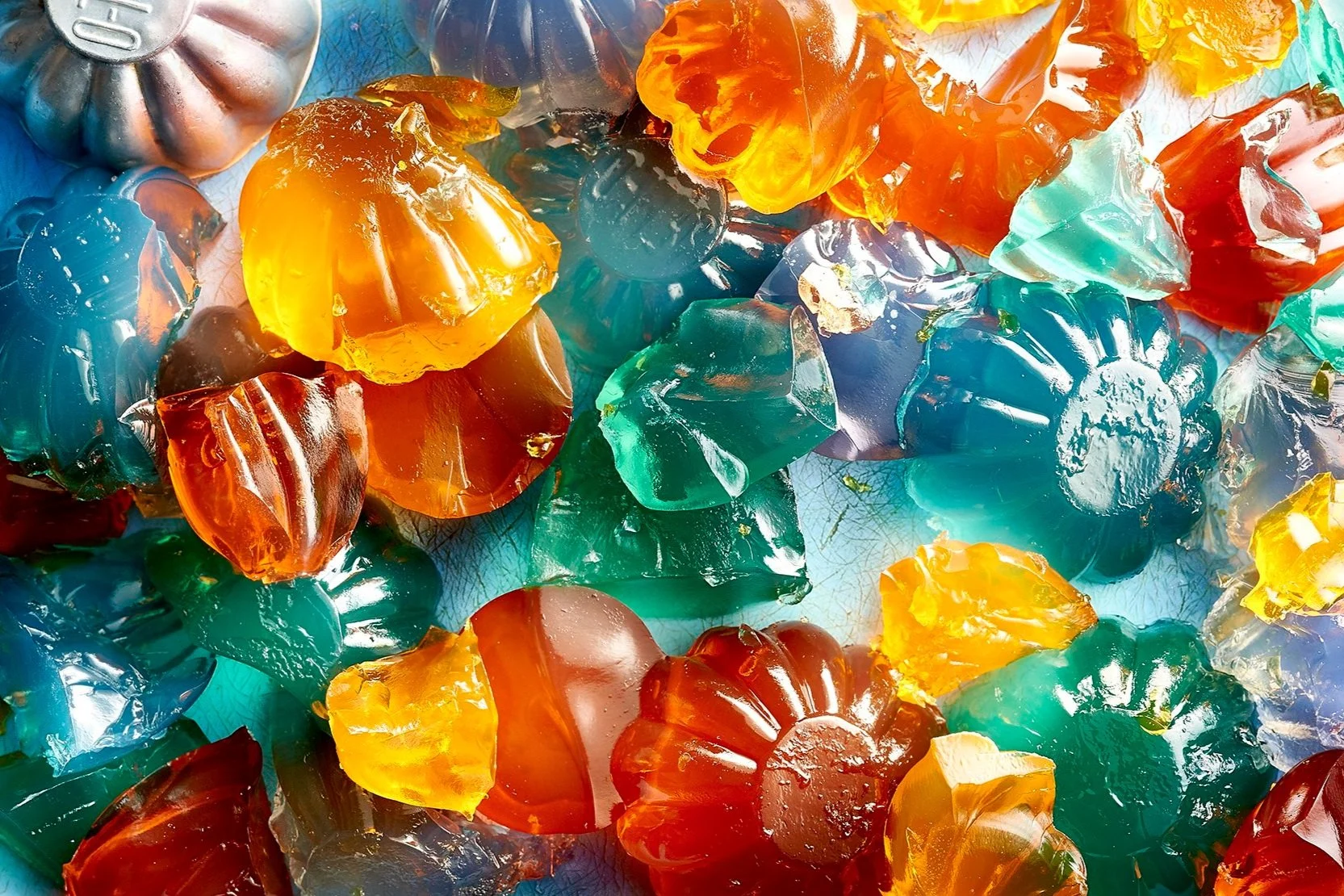 Charlotte Omnes & Ralph Smith - Colorful jello in various shapes and translucent colors, including orange, blue, and red, scattered on a surface.