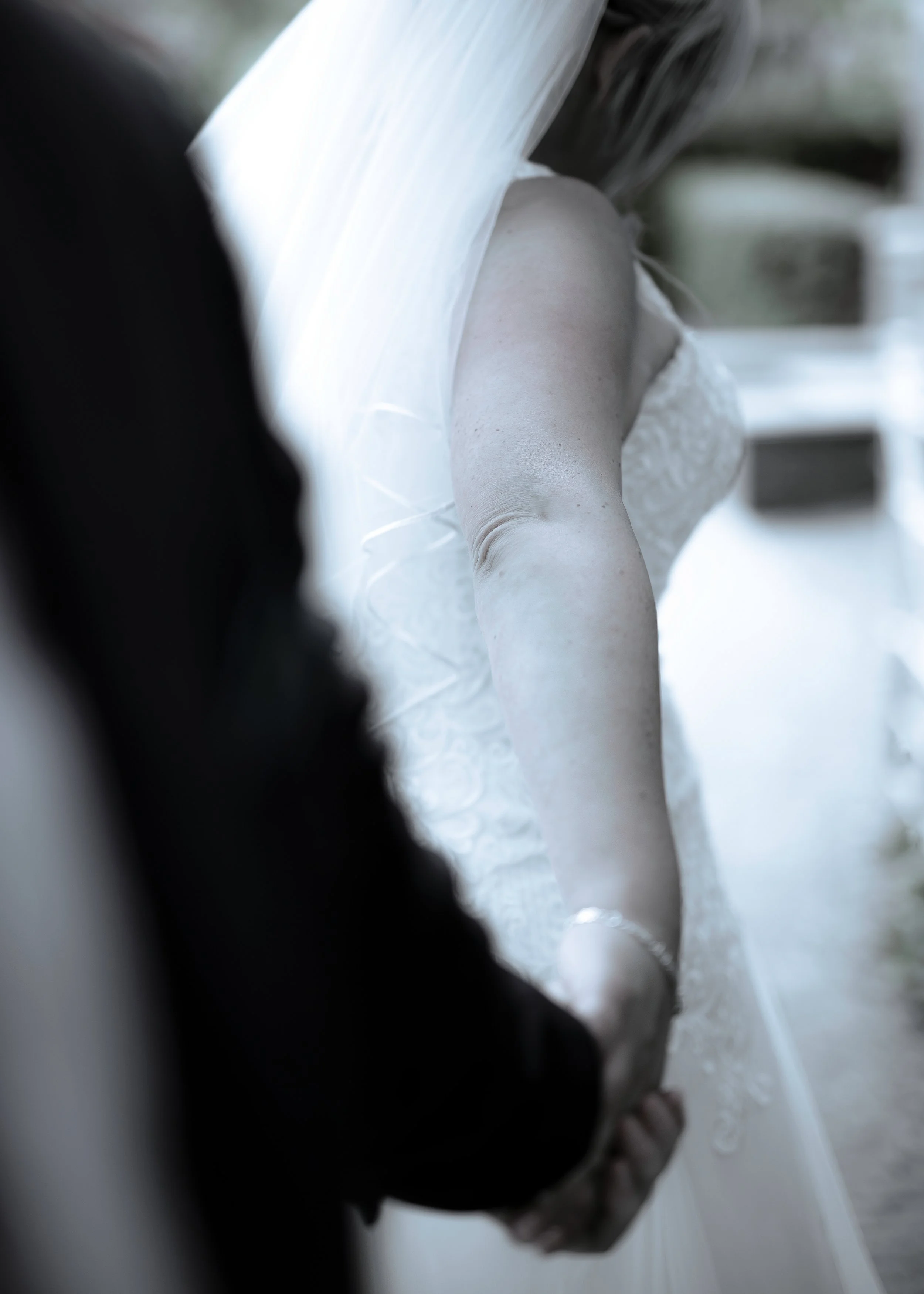 Person in a white lace dress and black blazer walking outdoors.