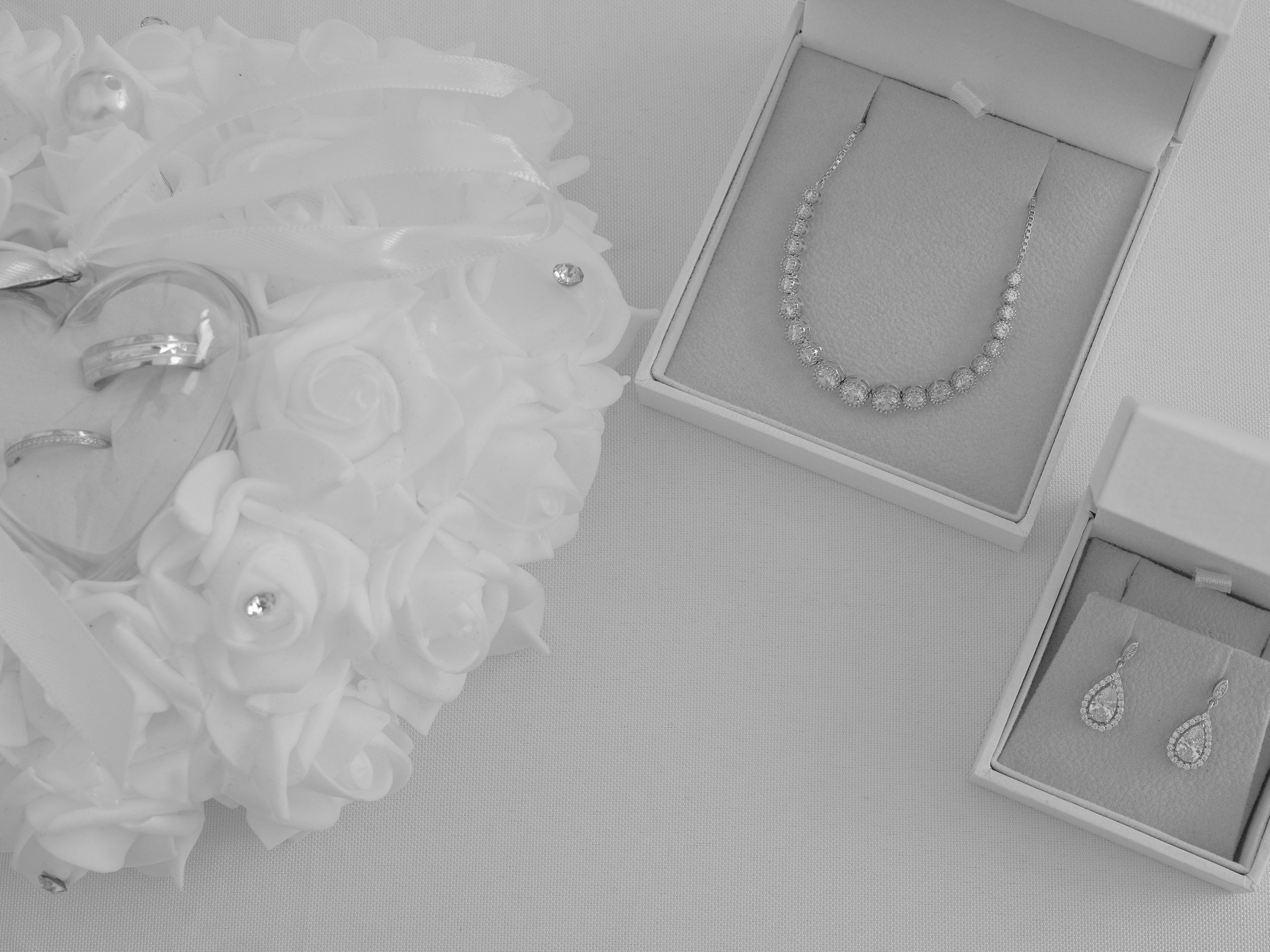 A jewelry box displaying a necklace with beads and a bracelet, with additional jewelry scattered on a white fabric surface.