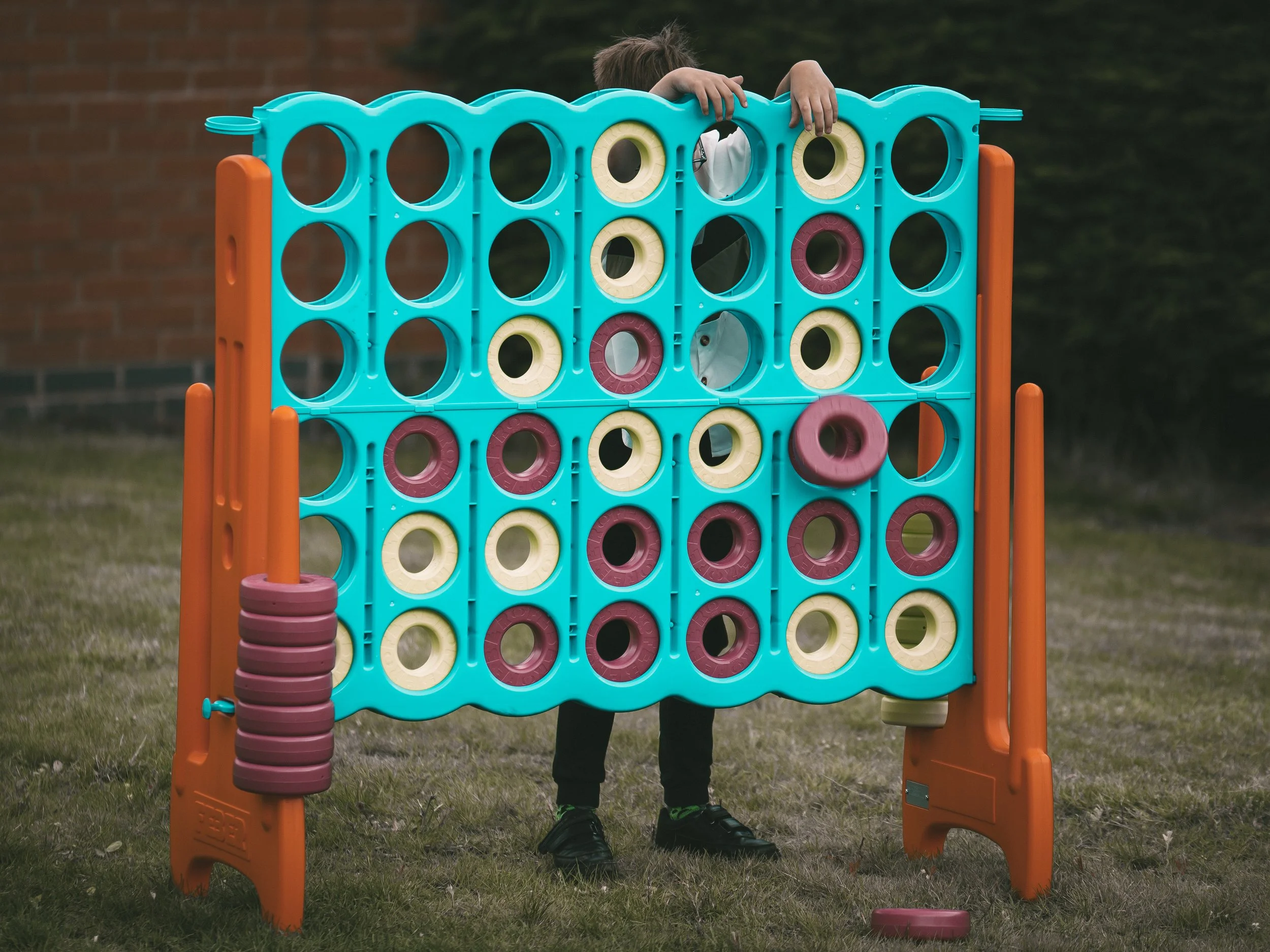 Child playing Connect Four outdoor game on grass