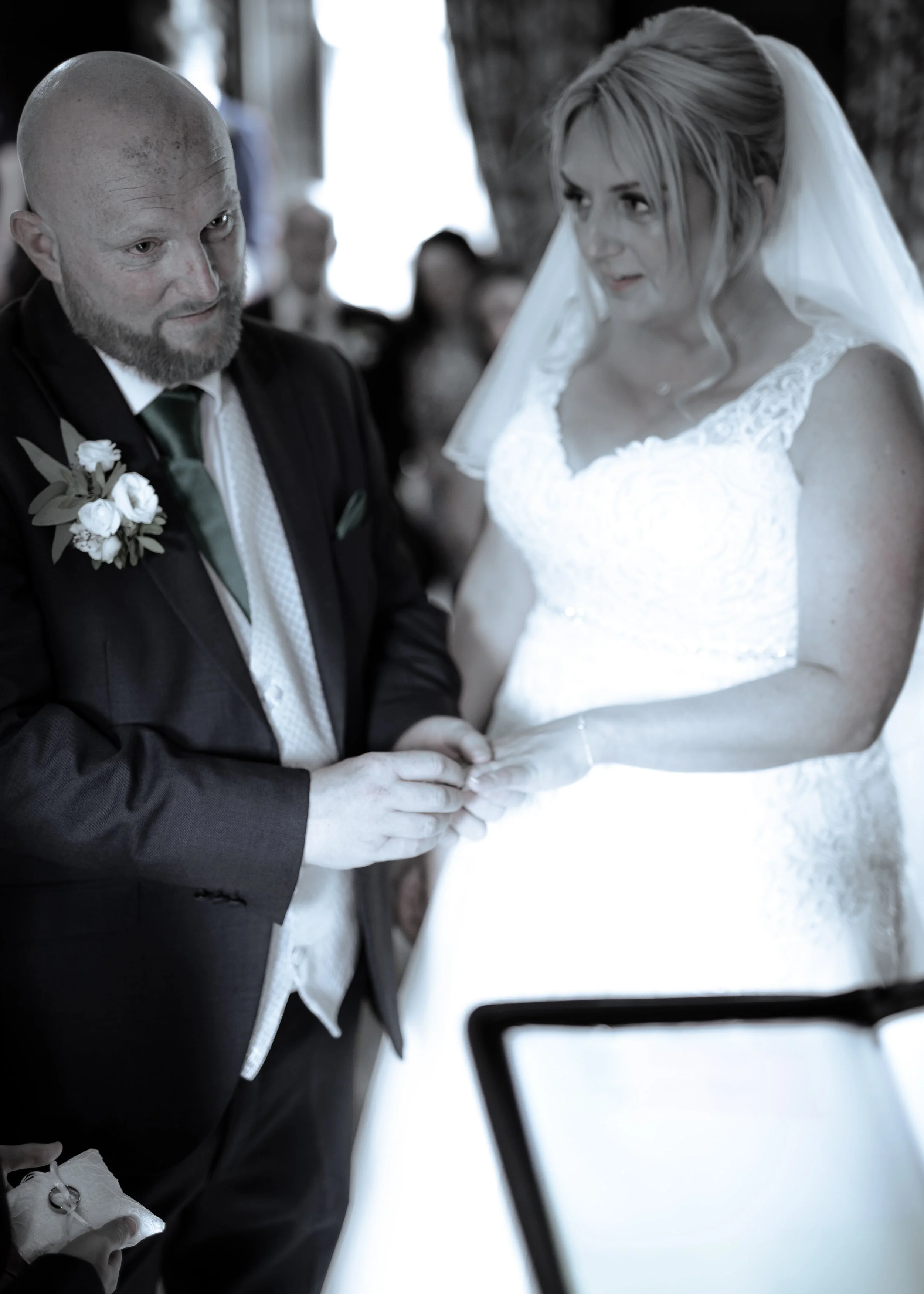 A bride and groom holding hands during their wedding ceremony, with the focus on their intertwined hands and expressions.