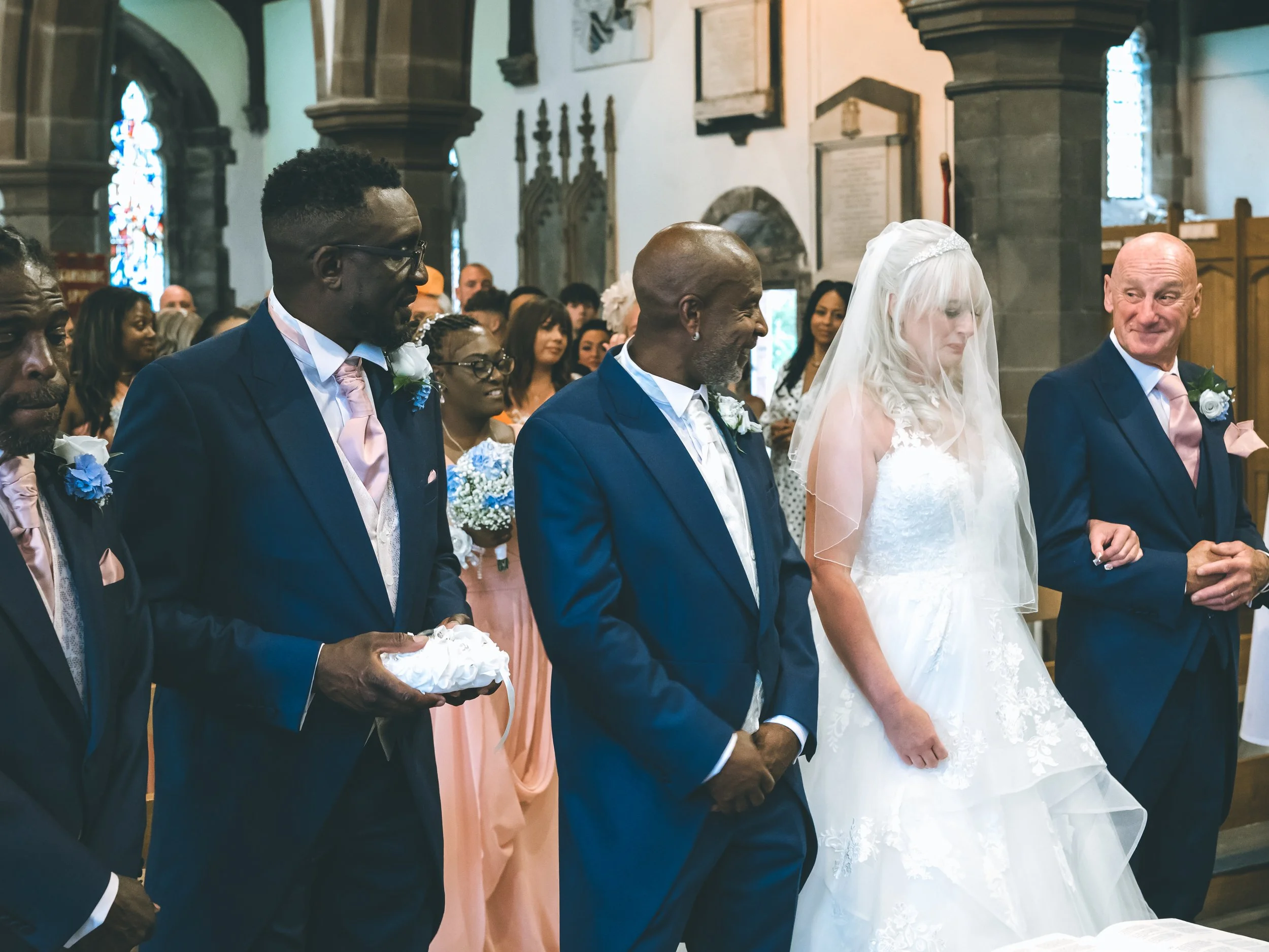People attending a wedding ceremony in a church, with some holding hands.