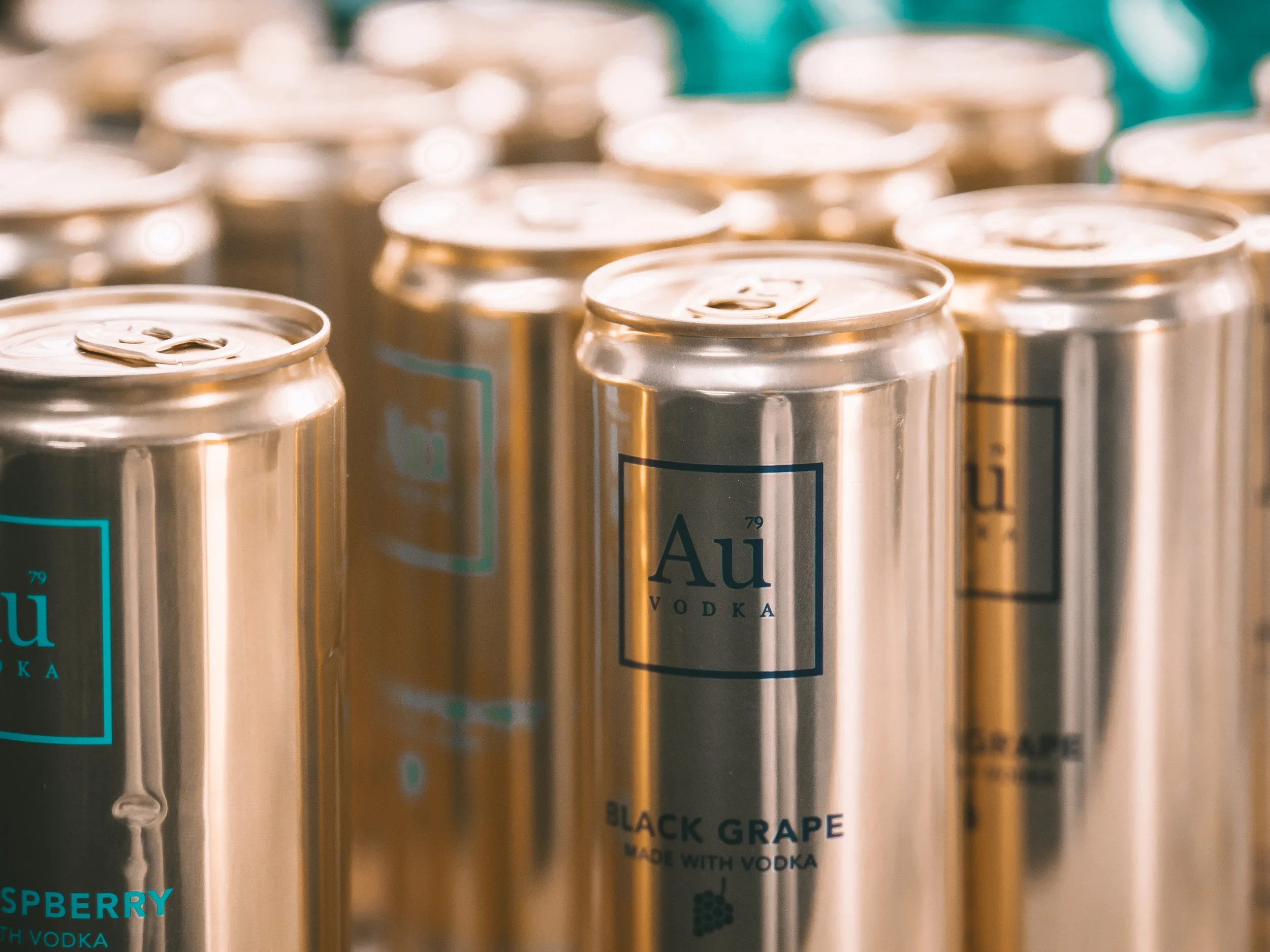 Close-up of cans labeled with vodka flavors, including black grape and raspberry, arranged in a display.