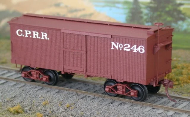 Model train car painted red with white lettering reading C.P.R.R. and No. 246 on a miniature train track.