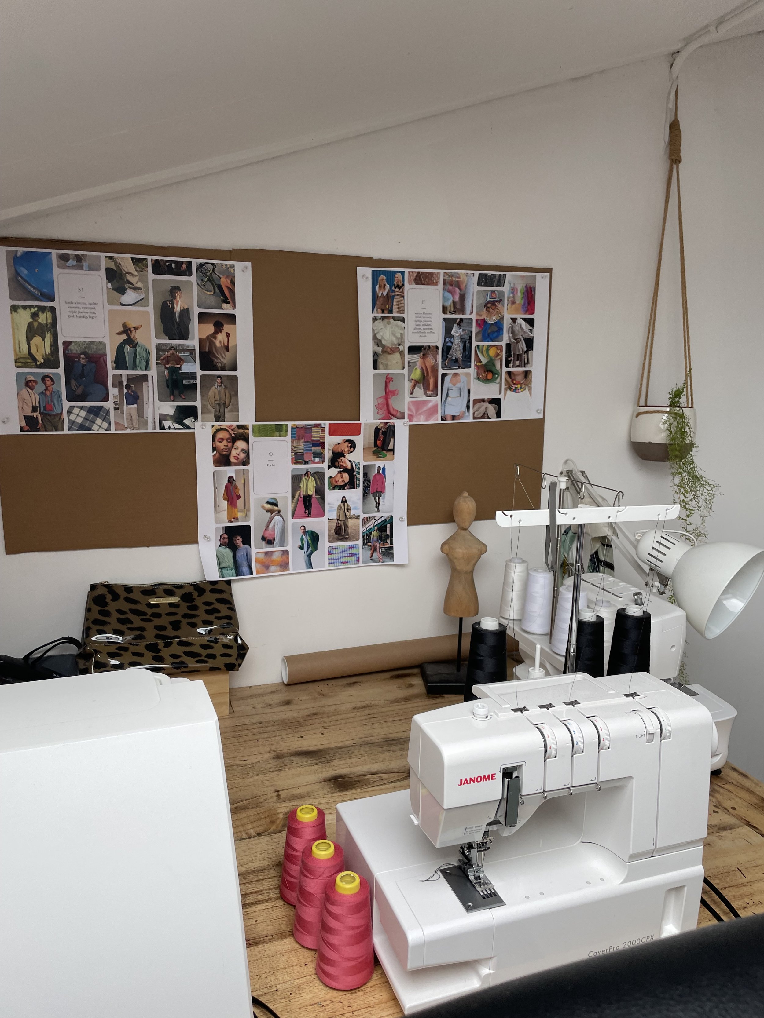 Binnenruimte met een bord met foto's van kleding, een naaimachine, viltstiften, mannequin en planten.