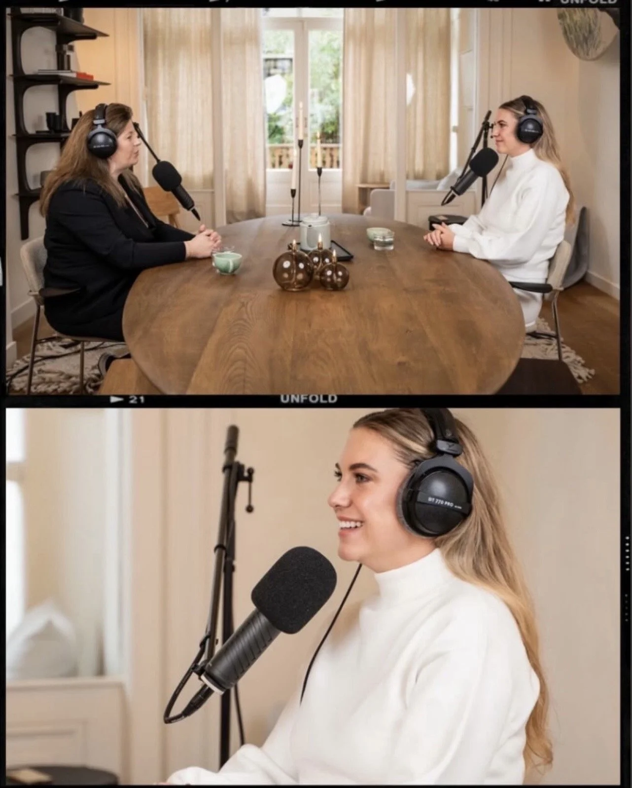 Een vrouw met lang blond haar en een witte trui zit voor een microfoon, terwijl een andere vrouw met bruin haar en een zwarte outfit tegenover haar zit, beiden dragen koptelefoons en nemen deel aan een opname of podcast. Ze bevinden zich in een gezellige, lichte kamer met grote ramen en beige gordijnen.