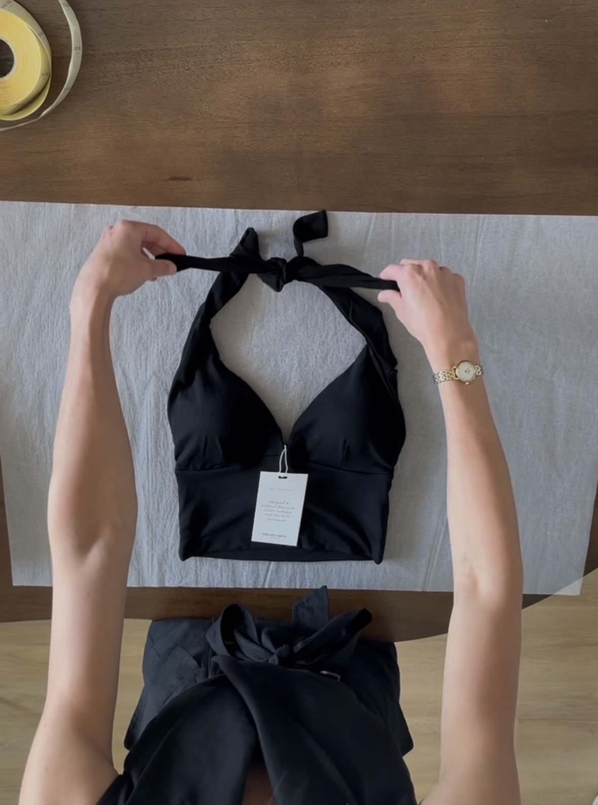 Persoon die een zwart bikini vasthoudt op een tafel met een rotan klokken op de hoek.