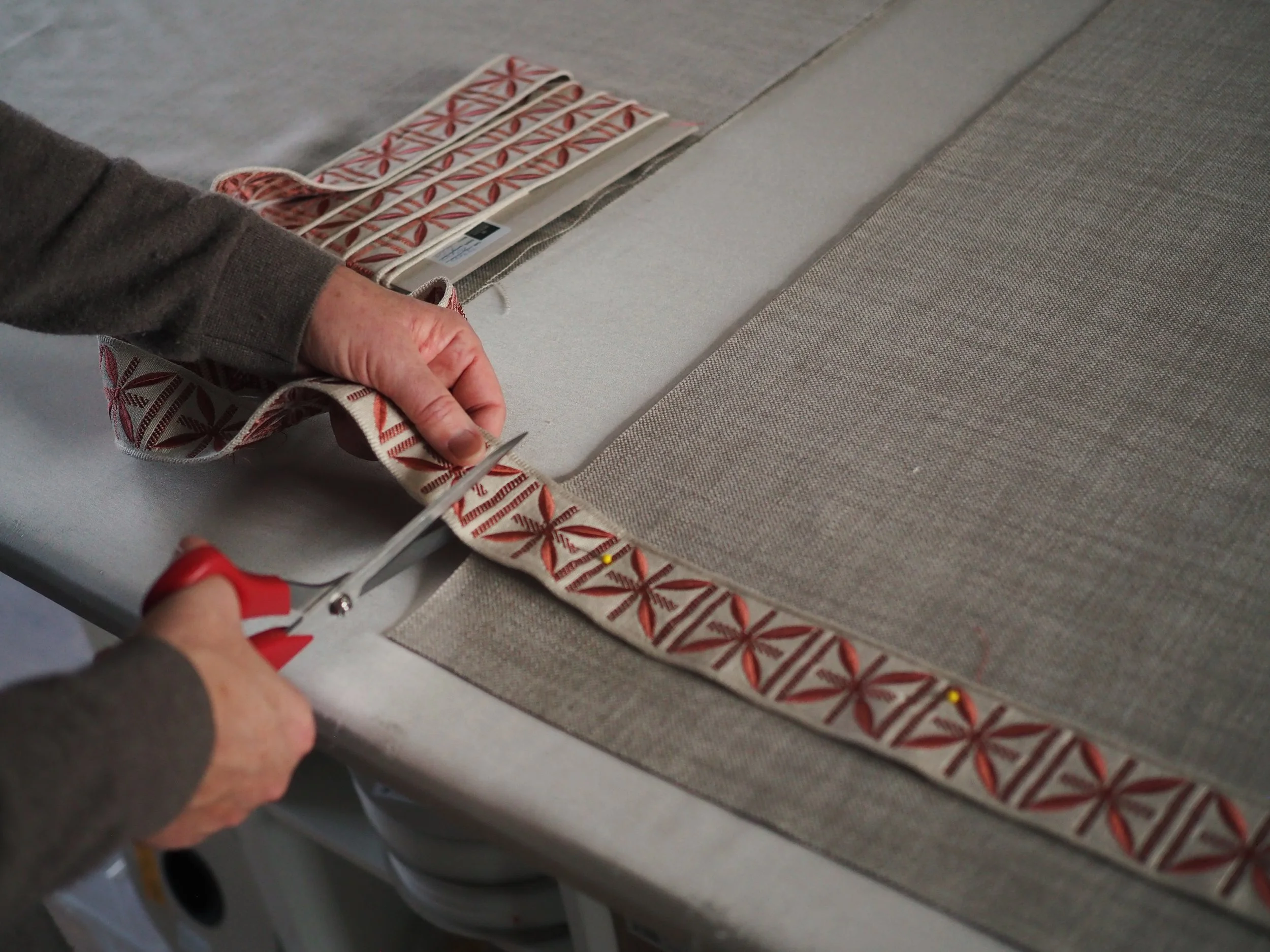 Person using scissors to cut a ribbon with a holiday pattern, likely at a celebration or event.