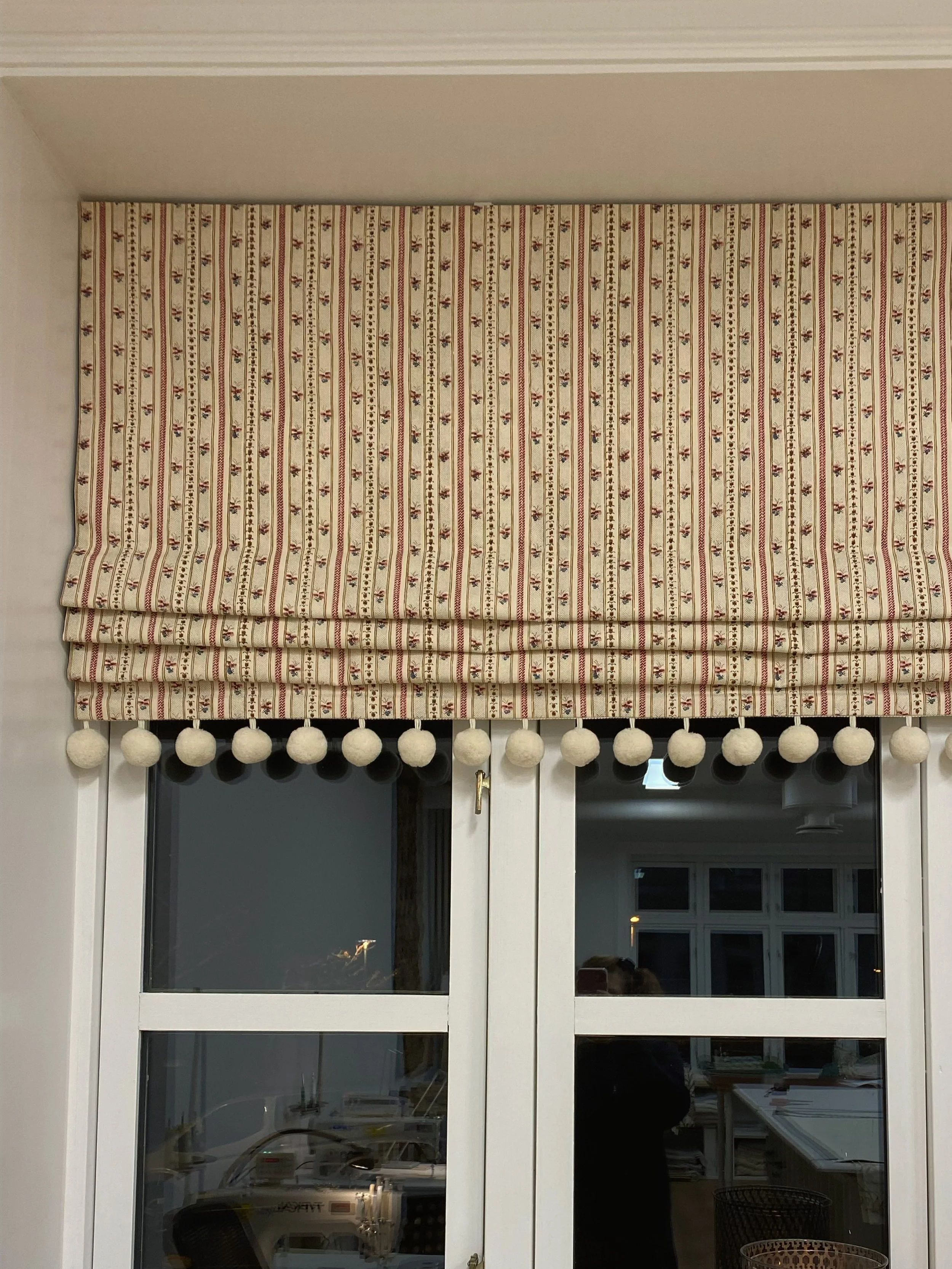 Curtain with a striped pattern and small floral design hanging above a glass door.