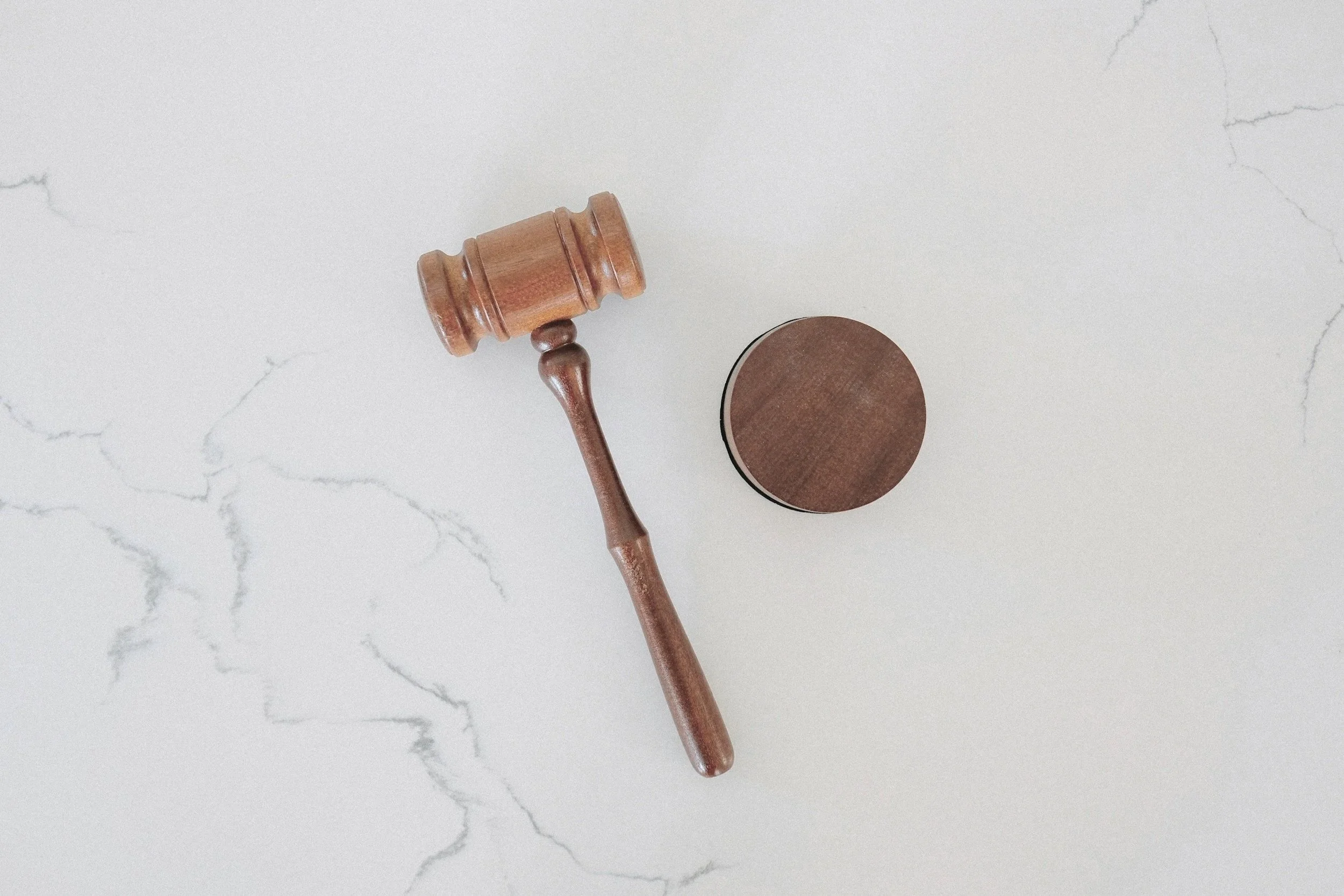 A wooden gavel on a white marble backdrop.