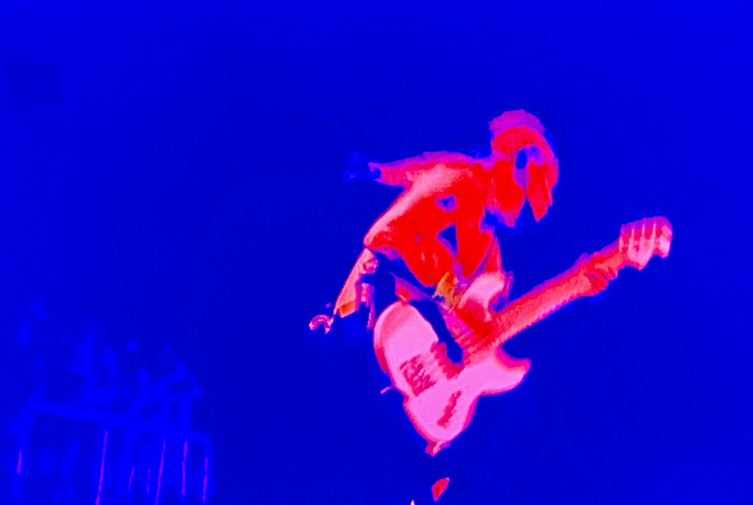 A person playing an electric guitar, captured in a vibrant blue and red color scheme.