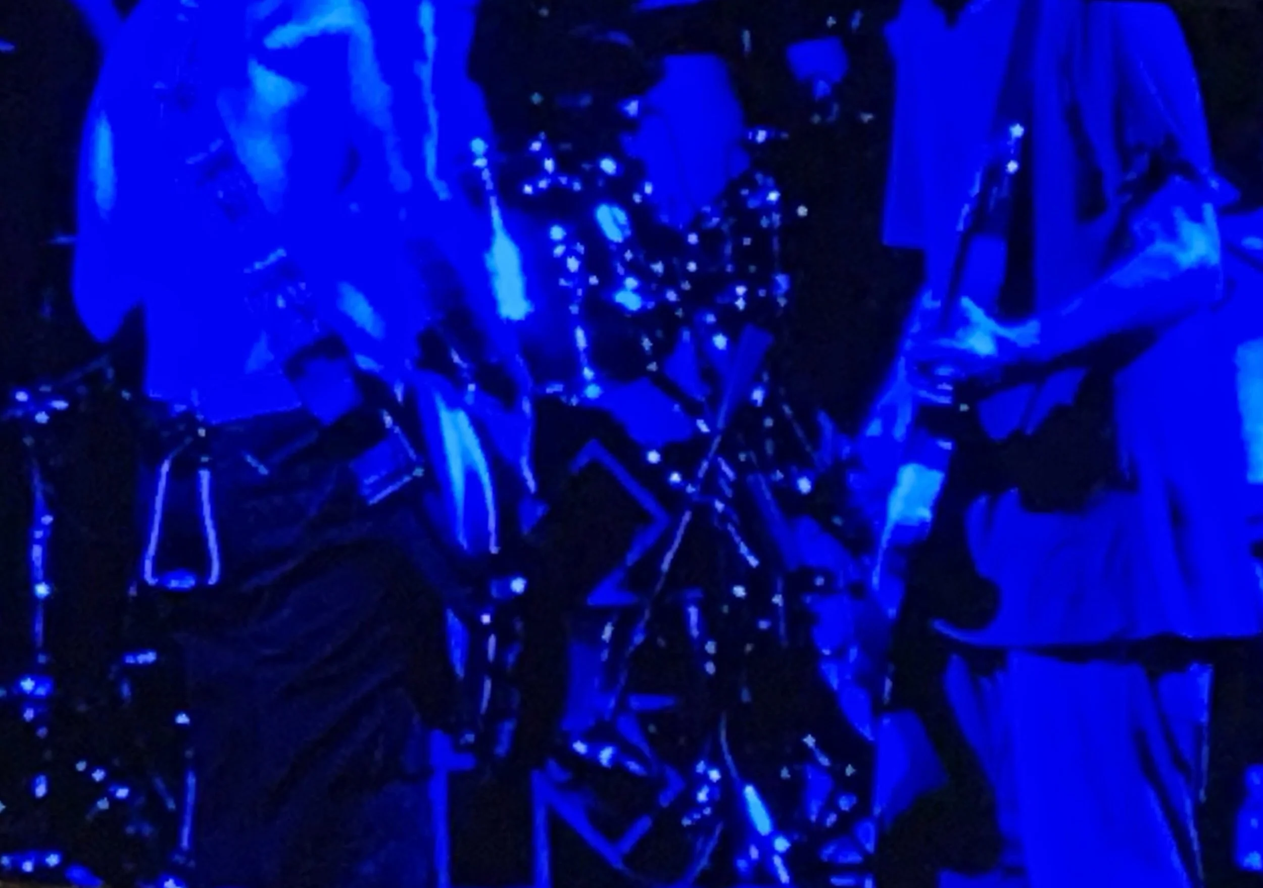 A group of people illuminated by blue light, playing musical instruments.