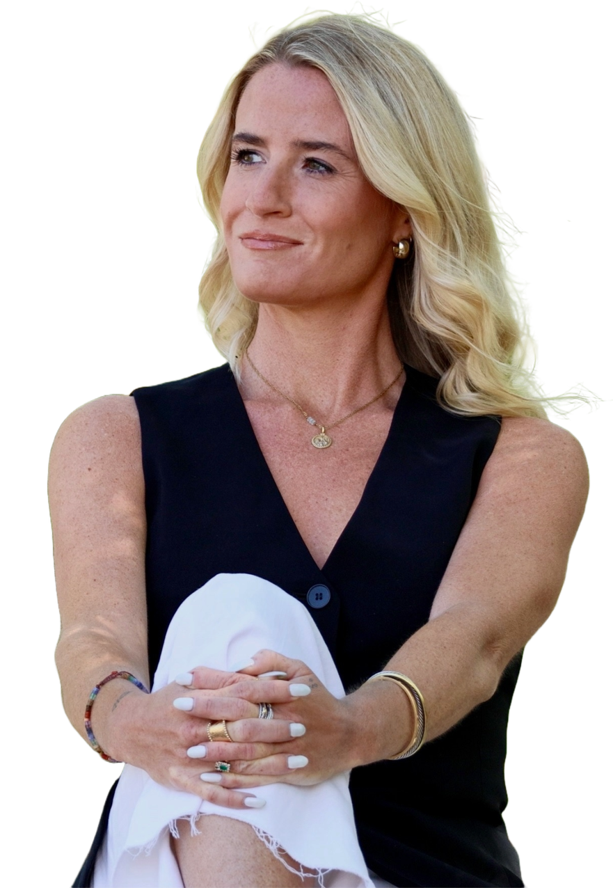 A woman with blond hair wearing a sleeveless dark top and gold jewelry, holding a white cloth.
