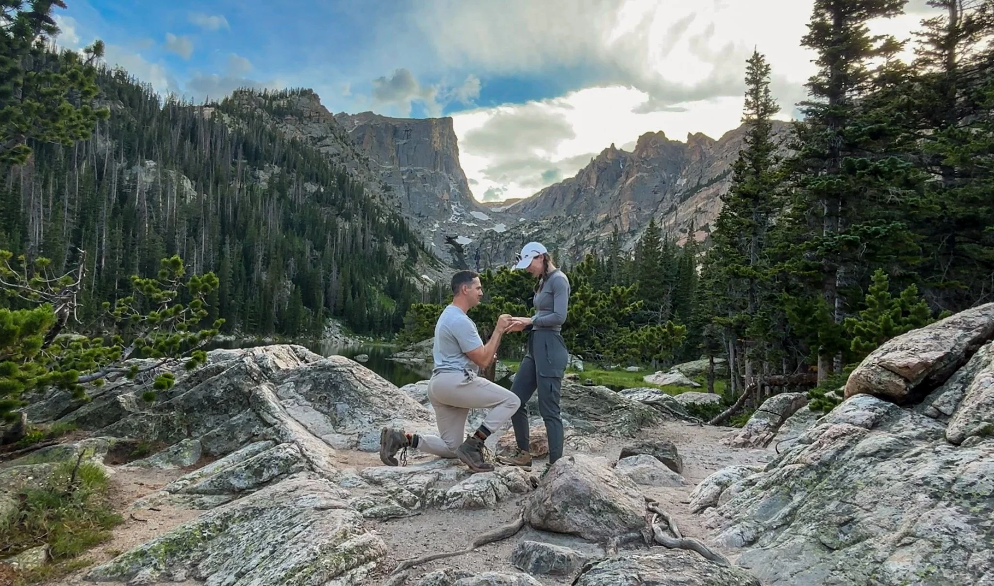 Man proposing to women overlooking Dream Lake in Rocky Mountain National Park in Colorado. Both wearing hiking gear