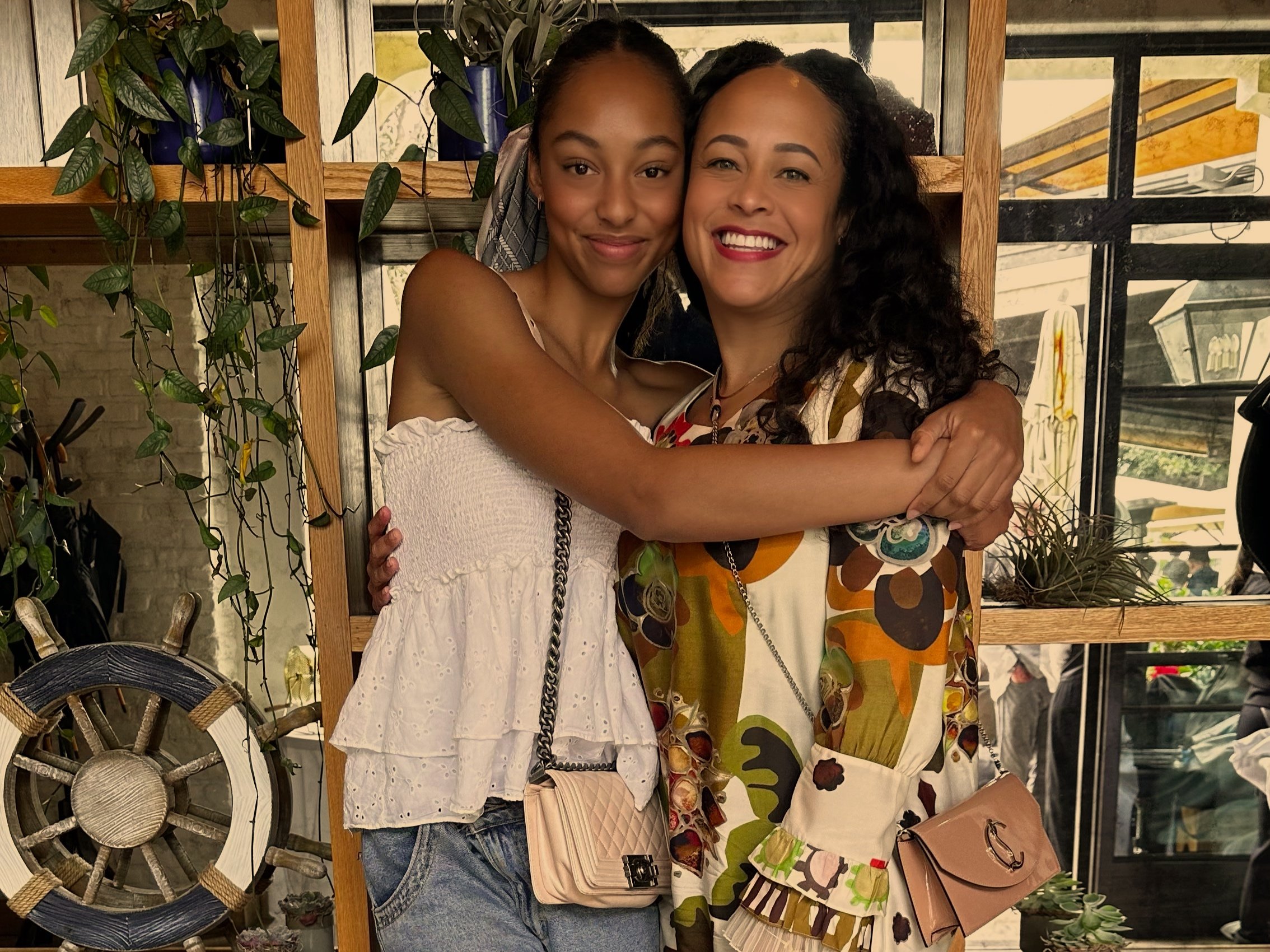Hugging women with ship wheel — joyful lifestyle moment rooted in connection and story.