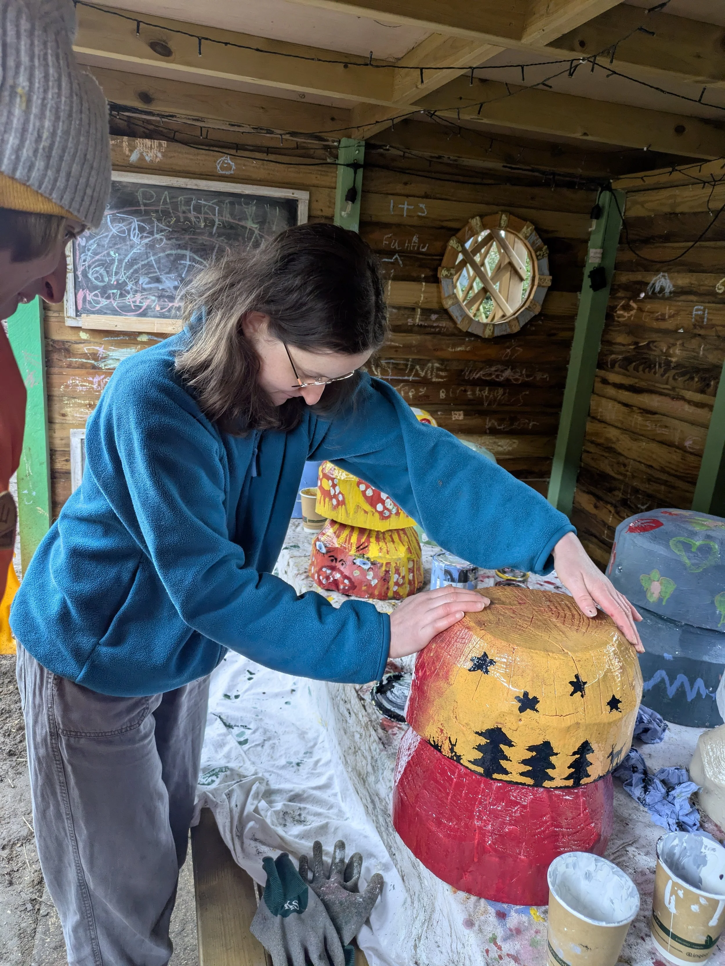 Lucy painting her mushroom with a sunset starry night scene