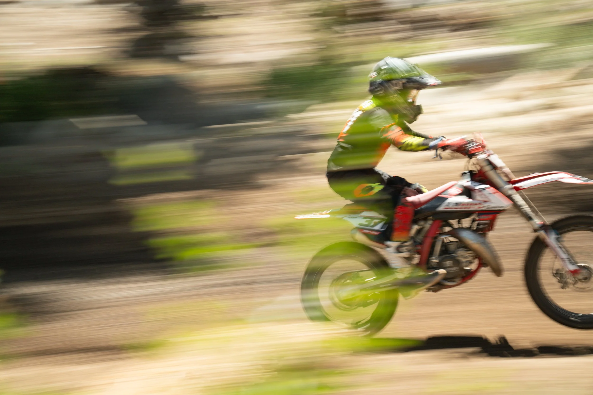 A person riding a motorcycle at high speed through a dirt trail in a motion-blurred photo.