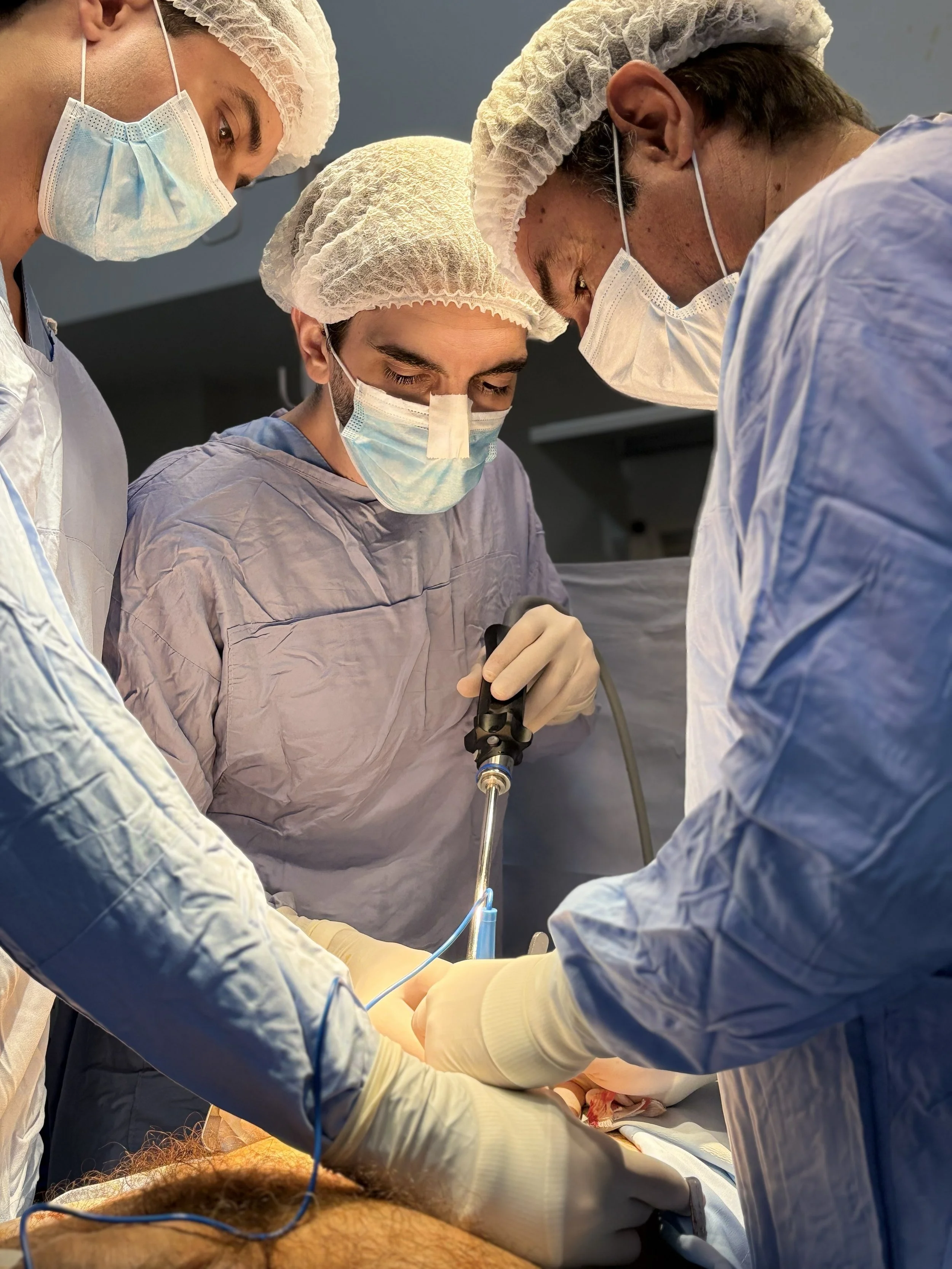 Grupo de médicos en una operación quirúrgica, usando mascarillas, gorros y batas, trabajando en equipo