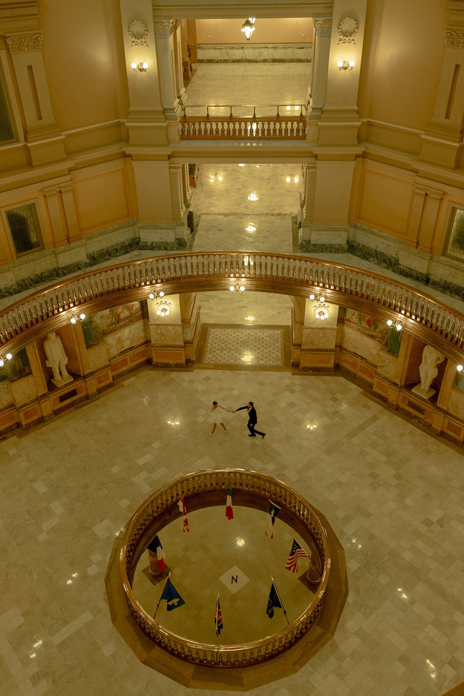 Bride and groom chasing each other in the Topeka State Capitol during their engagement photos.