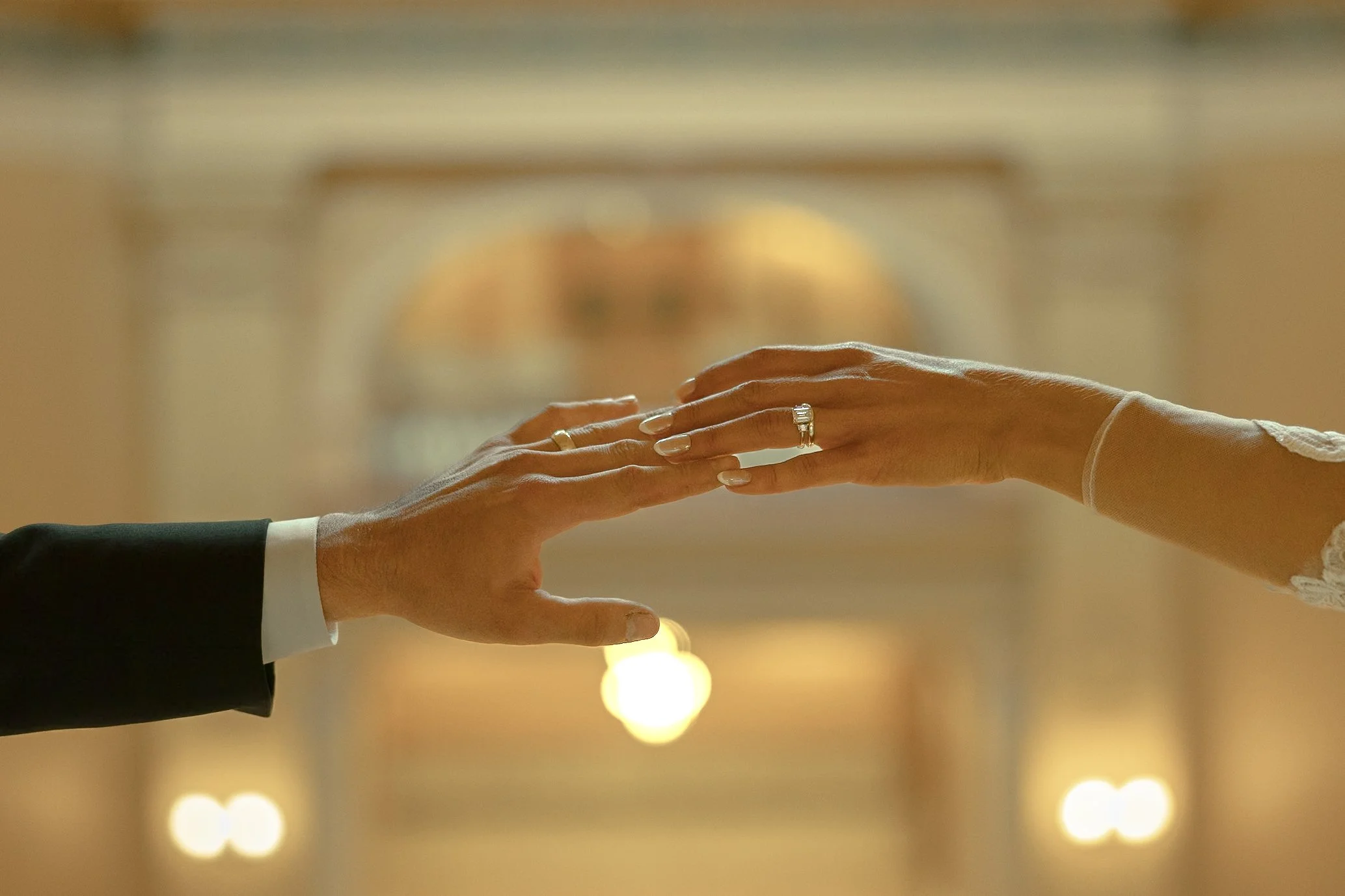 Bride and groom touching hands and showing off their new wedding ring and band on their wedding day at the Topeka State Capitol Building.