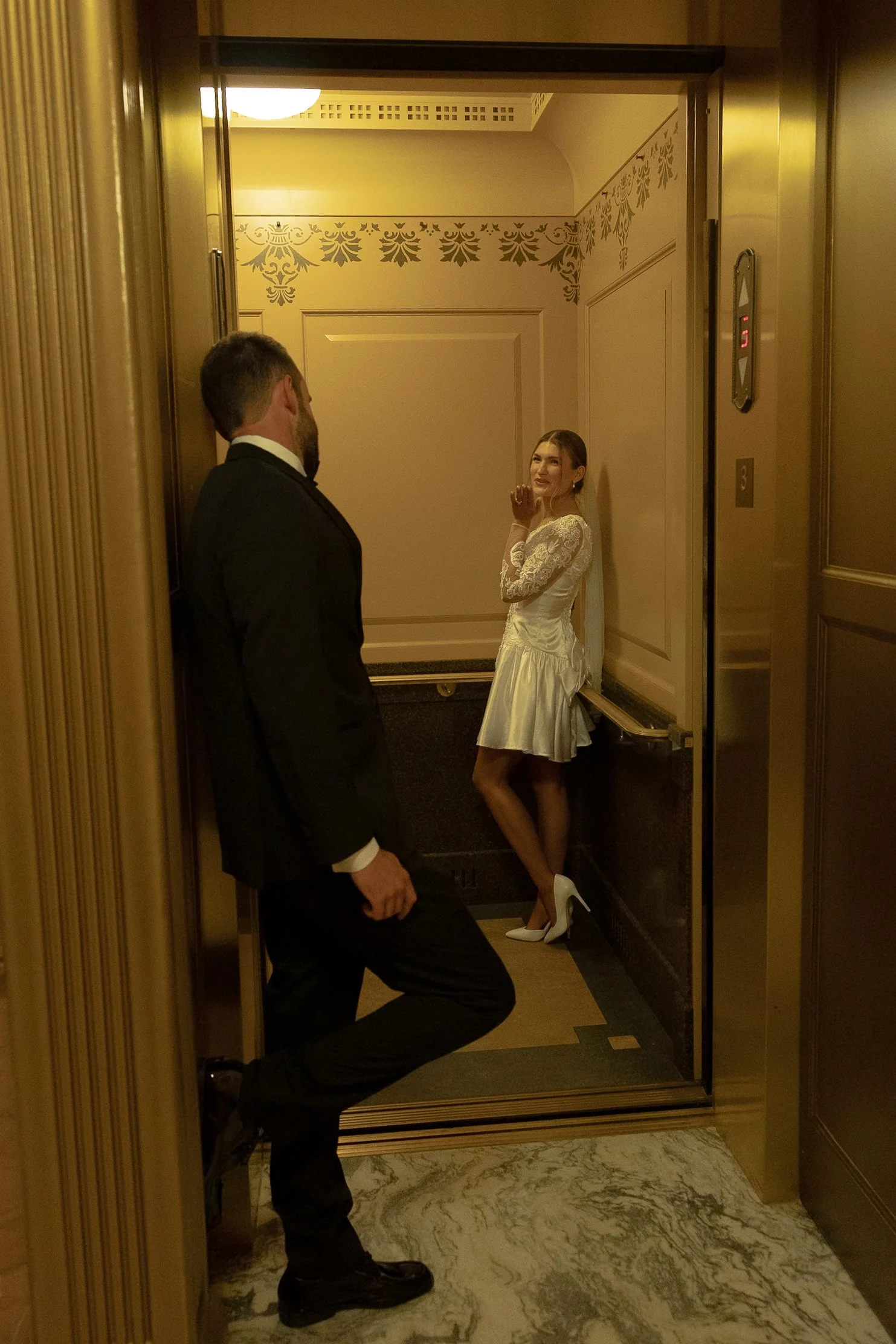 Bride and groom blowing kisses in the elevator inside the Topeka State Capitol.