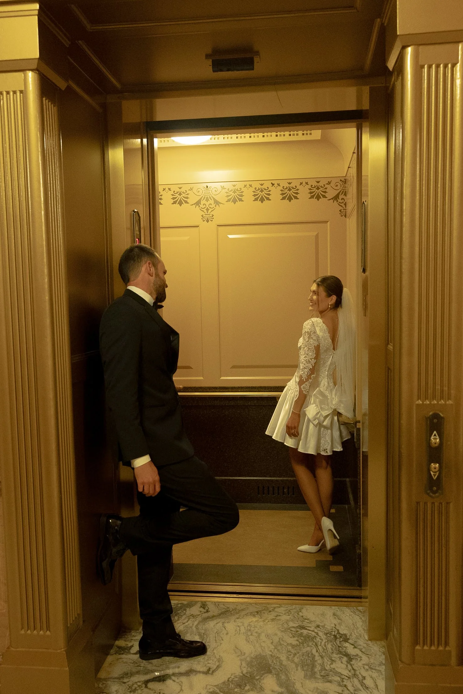 Bride and groom romantically looking at one another on the elevator inside the Topeka State Capitol.
