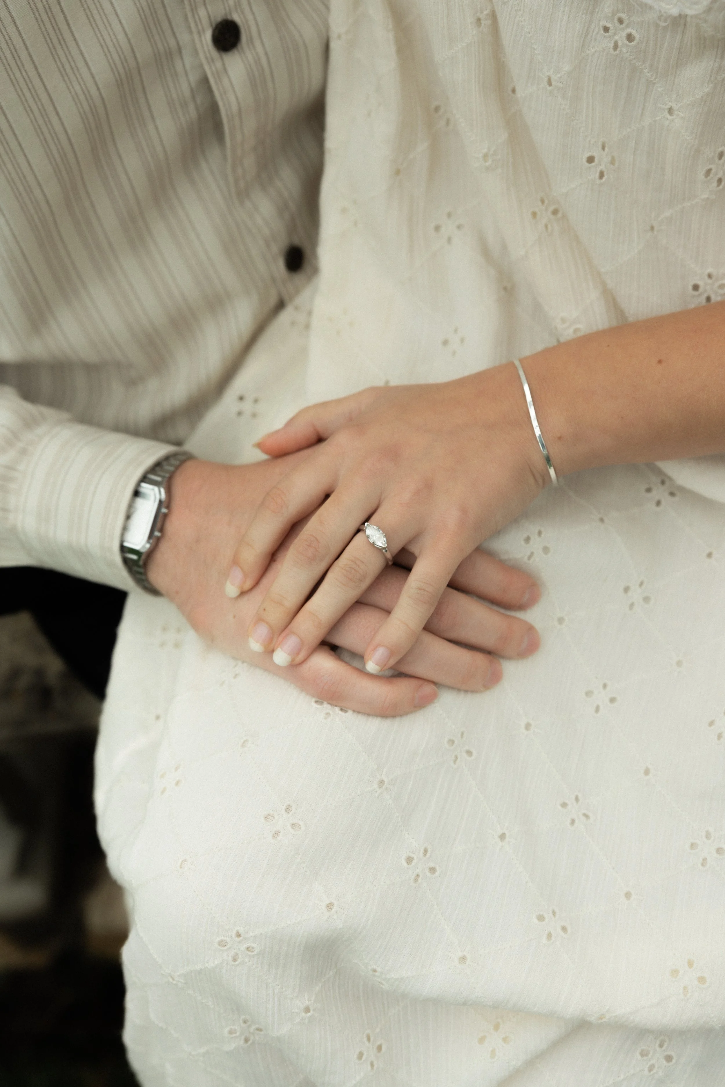 Close-up of a wedding ring on a woman's finger, resting on a man's hand during a wedding or engagement ceremony.