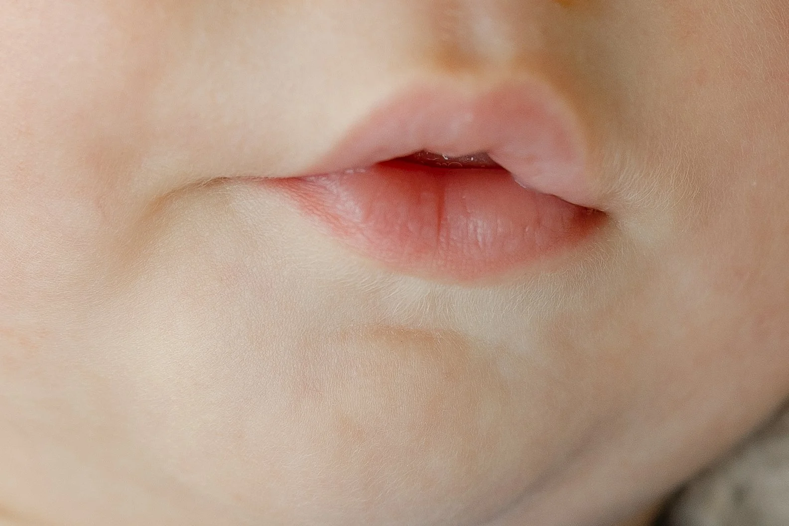 Close-up of a baby's lips and mouth, showing soft skin and slightly parted lips.