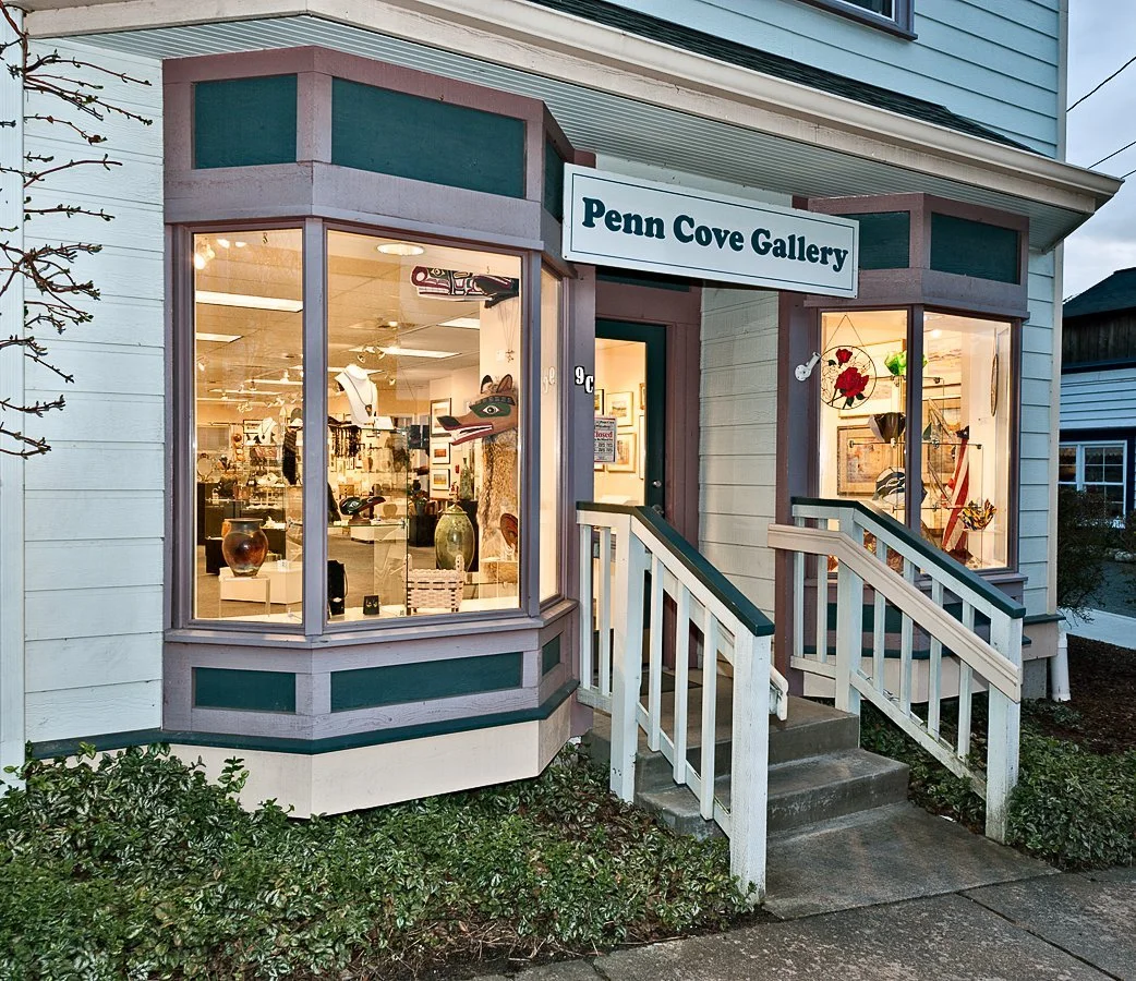 Exterior of Penn Cove Gallery showcasing art and gifts inside, with large display windows and a small front porch with stairs.
